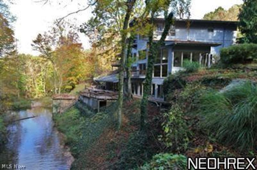 Very unique, Frank Lloyd Wright type home built into a rock hill side with many of natures beauties to enjoy. Enjoy a catch for dinner by casting from one of the 5 decks totaling 1500 sq. ft and overlooking a stocked pond & waterfalls that you can easily catch a 15" striped bass. Plenty of woods and natural canyons surrounding the property. This home sits back a 1/3 mile long paved and is being offered w FREE GAS!  In 2010: high efficient gas/AC unit installed, the roof was replaced and house painted. Brand new updates in 2013: Driveway redone, repairs throughout the home with drainage, downspouts, skylight updates, new deck lighting, professionally refinished and re-stained decks and much more! Enjoy the added convenience of a dumbwaiter system with recent upgrades for transporting laundry and groceries throughout the house! Massive lower level rec room of approx 1400 sq ft. features built in sandstone rock formations, custom built oak & tile 10 seated bar. Owner shall convey 49% of m