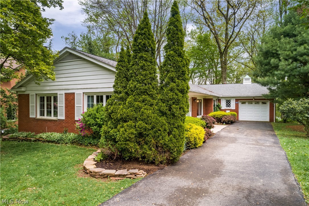 A hidden gem tucked along meandering Overlook Drive in Kent’s tree-filled University Heights neighborhood! This 3BD, 1.5BA brick ranch is close to the KSU campus, bus stops, major routes, vibrant downtown Kent restaurants and shopping, and the Farmer’s Market in winter. Experience peaceful and comfortable one-level living in a home with an abundance of natural light. The spacious L-shaped living/dining room boasts a built-in wall unit, gas fireplace, and beautiful picture windows. The recently renovated eat-in kitchen (2020) has Cambria quartz countertops, Italian tile backsplash, and touch-activated faucet and hosts plentiful cabinets and a convenient laundry nook. Adjacent to the laundry and mudroom/garage is a 4-season step-down sunroom with panoramic windows that opens onto the composite deck overlooking the private and maintenance-free backyard. Three generous bedrooms feature large built-in closets, and two have freshly coated parquet wood floors. The primary bedroom features an