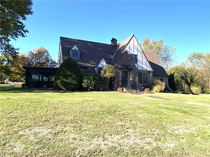 East Palestine, OH - Unity Twp. – Located just outside the Village of East Palestine is where you will find this stunning 5 BR, 3 bath Tudor style home.  This captivating brick and stone home has a 1 car integral garage, a 2-car detached garage, PLUS a 30 x 30 outbuilding with running water all sitting on 1.375 acres! Once you step inside this warm and inviting home you will be enchanted by its classic architectural details.  The first floor offers an updated kitchen featuring cherry cabinetry, solid surface countertop, stainless appliances and a breakfast bar. The formal dining room is adjacent to the kitchen and offers a built-in hutch, parquet flooring and on the ceiling, various crown molding. In the expansive living room you will find a gas log fireplace, several arched niches and glass paneled French doors that open to the 14 x 22- four season room. Also located on the first floor is the primary suite with an updated bath, 2 additional roomy bedrooms and the second full bathroom. One floor living is possible in this home however if more living space is needed you will find an additional 900 square feet on the second floor featuring 2 more bedrooms, the 3rd full bath, an 18 x 18 great room, a large bonus room and a loft. Most of this amazing home has been updated and is a perfect blend of historic charm and modern comforts. Some of the updates include: a furnace, roof, windows, electric, plumbing, copper gutters, range, refrigerator and dishwasher.  A complete list of updates available upon request. This fabulous home is move in ready, offers a flexible floor plan and would be perfect for your family! Don’t miss your opportunity to make this enchanting property your next home!  This property is conveniently located a short distance from the OH/PA state line, approx. 25 minutes south of Youngstown, OH, 40 minutes from the Pittsburgh International Airport, 1 hour from Pittsburgh and 1.5 hours from Cleveland, OH.