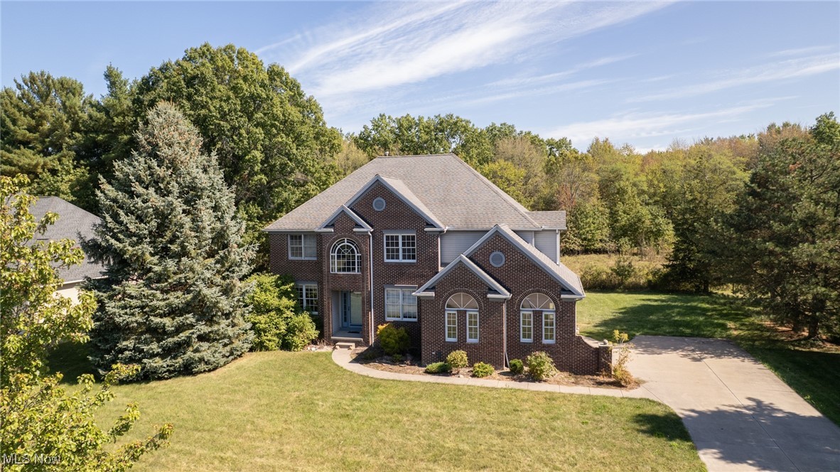 Nestled in Vermilion, a quaint coastal city on the shores of Lake Erie, prepare to embrace lake breezes, sunset strolls along the coast, and a relaxed Vermilion lifestyle just moments from the quaint downtown. The brick-front façade of this home welcomes you to a premium lot that backs to a serene, wooded sanctuary, offering privacy and a sense of timeless elegance. Inside, soaring ceilings elevate the two-story foyer and great room, flooding the space with natural light that makes daily living bright and effortless and entertaining a joy. The chef-inspired kitchen anchors the home with modern white cabinetry, abundant countertop space, and a generous eat-in area that overlooks the deck and lush yard, while easy access to the adjacent dining and living spaces keeps gatherings seamless. The main floor includes a fifth bedroom with a full bath—perfect for guests or a quiet in-law suite—plus a private office with French glass doors opposite to the dining room and a convenient first-floor laundry, all arranged to maximize flow and flexibility. The basement is fully finished with half a bath and the capacity to become a full bathroom, presenting a sizable canvas for a future media room, gym, or play space, with ample storage. Outdoors, a spacious deck with a motorized sun awning beckons warm evenings and a hot tub for snowy days, alfresco dining, and sunset-watching, while the surrounding yard and wooded backdrop deliver serene privacy. Additional highlights include energy-efficient windows, recessed lighting, premium millwork, and a thoughtfully designed layout that balances luxury finishes with everyday practicality, making this residence not just a home but a refined lifestyle in Vermilion’s most coveted community. This home blends small-town charm with easy access to marinas, cute shops, and unique lakeside dining in a city that has been voted as Ohio’s Best Beach Town on the East shores of Lake Erie.