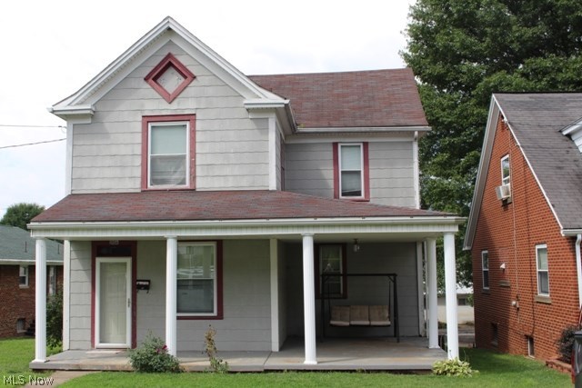 Two story home with patio and back porch over one car garage. Wrap around front porch. Asbestos shingle siding.