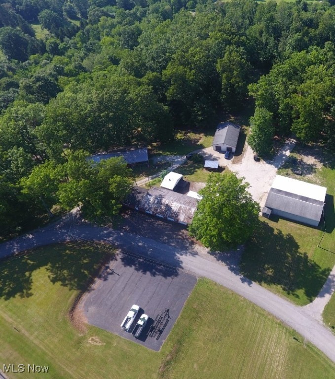 Incredible opportunity on just under 6 acres in the scenic rolling hills of SE Carroll County & only 10 minutes from Carrollton. Starting with the house, this brick ranch features 3 bedrooms, 2 full baths and a beautiful wrap around deck for outside living & entertaining. The wrap around deck has a 16x28 covered portion as well as a 76x11 open deck. Stunning sunsets overlooking rolling wooded hills provide a spectacular end to your day. The main floor features a oak kitchen (appliances stay), dining room, large 28x20 living room, master bedroom with two spacious closets, 2nd bedroom, full bath and mudroom. Two patio doors lead from the dining room and living room onto the scenic deck. The walk out lower floor adds a second full bath, family room, 3rd bedroom, laundry room & bonus room that could certainly be a fourth bedroom if needed. A new wood boiler system in the wood shed was recently installed which heats the house (also has a fuel oil furnace), the 5 bay garage (also has a fuel oil furnace) and the 32x48 garage if desired. All the outbuildings will be a huge bonus for the right buyer featuring a 30x108 5 air conditioned bay garage with attached office, 1/2 bath & storage room, 32x48 finished heated garage convenient to the home and a 52x64 3 bay garage. Storage could easily accommodate 20+ cars for a collector or there are endless home business opportunities. 10x16 storage shed. The 5 bay garage and the 52x64 3 bay garage are metered separately for electric. A separate parcel across Raven Road is also part of the land including the paved pad. A new septic system was installed in 2022 offering peace of mind to the new owners. Mineral rights owned will transfer to the new owners. The land offers some magnificent hardwood trees offering nice shade and a beautiful park-like setting for your families enjoyment. The owners have spent endless hours of work along with substantial investments over the past 3 years. Be sure to view the 3D virtual Matterport tour.
