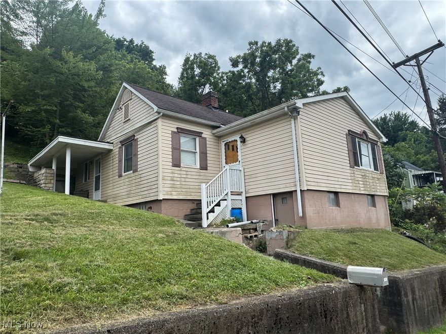 Located in Bridgeport Ohio, this one-story ranch offers privacy with mature trees and multiple outbuildings. The property features a 44 x 40 oversized detached garage with two 13.6 overhead doors, ideal for commercial use or a contractor's workspace. An additional detached garage at the top of the hill provides ample room for outdoor equipment and storage. The home itself is a fixer-upper with strong potential, making this a versatile property for both residential and business needs.