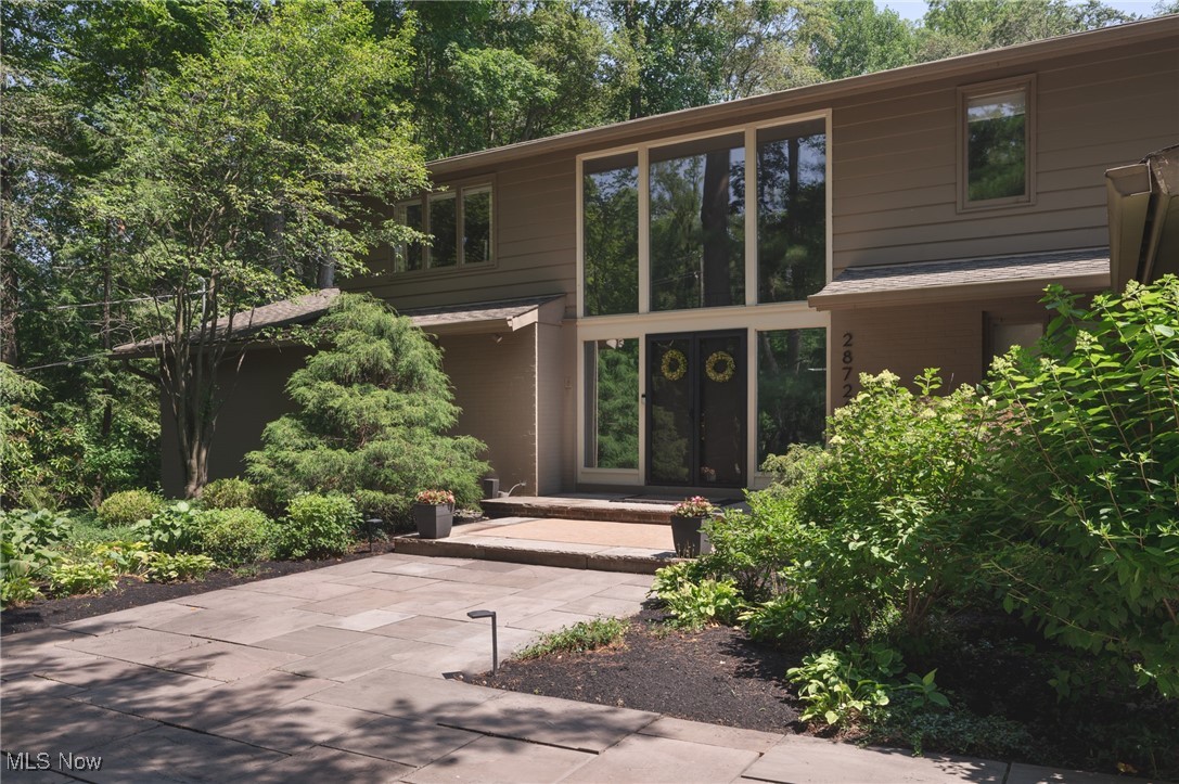 Tucked back from the road and surrounded by woods, this Pepper Pike stunner feels like the world’s most luxurious glass treehouse. At once striking and serene, its architecture is timeless mid-century modern with a sculptural presence and spaces that breathe with light and nature. The experience begins the moment you enter. Sunbeams become art—spilling across the terrazzo, casting a glow on the gleaming stone, and bouncing shadows off the warm wood. In every season, the natural light is extraordinary. Soft in the morning, golden in the afternoon, and absolutely magical in winter as snowflakes dance on the skylights. The living room anchors the home with its soaring ceiling and dramatic fireplace as the walls of windows take you out to your own forest and lush surroundings—equal parts serenity and statement. The custom kitchen speaks in a quiet European accent. Flawlessly functional, artfully minimal, and every detail intentional. The dining room is sophisticated and sleek. The first-floor primary suite is your sanctuary, opening directly to the patio. Its spa-like bath is a study in calm, while integrated closets add elegant practicality. Upstairs, the layout flexes for family, guests, work, and wellness. One bedroom is now an office and guest-ready bedroom, another a tucked-away fitness room. The vintage baths are pristine and preserved. Back outside, the deck wraps the home in possibility—coffee at sunrise, wine at dusk, quiet moments in between, or a fabulous garden party any time of day. Every view is green. Deer, bunnies, and more become your friends. This is not just a home. It’s a feeling—of clarity and connection. Whether you're a mid-century modern enthusiast or simply someone seeking beauty, balance, and quiet luxury, you will know that you are home here. Private. Elevated. Effortless.