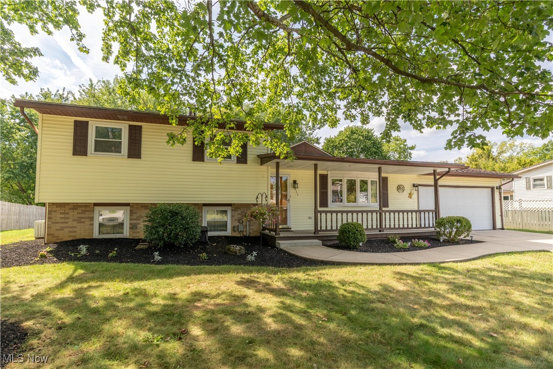 Welcome to this beautifully maintained 3-bedroom split-level home, perfectly situated on a tree-lined lot offering both privacy and comfort. Featuring a spacious 2-car extra-deep garage, this property also boasts a newer driveway and walkway, leading to a covered front porch—perfect for relaxing on quiet evenings. Inside, you'll find an inviting main level with a bright living room featuring a large picture window, seamlessly connected to the dining area with hardwood floors and a sliding glass door that opens to a maintenance-free composite deck. This covered deck overlooks a fully fenced, private backyard—beautifully landscaped and ideal for entertaining or unwinding. The kitchen offers oak cabinets and black appliances, providing a functional space ready for your personal touches. The lower level features a spacious family room with full-size windows, offering plenty of natural light, as well as a convenient laundry room. Upstairs, you'll find three comfortable bedrooms, all with hardwood floors beneath the carpet, and a full bath.