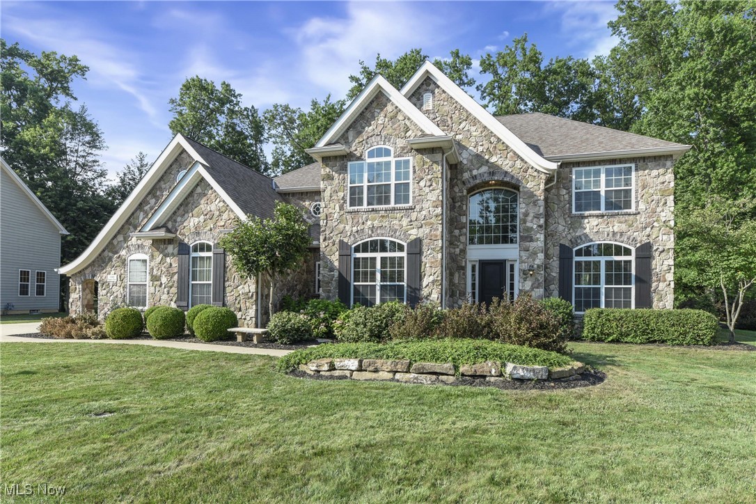 Prepare to be moved! Welcome to 32480 English Turn, Avon Lake, OH 44012. This well-maintained two-story colonial features a classic stone façade and offers spacious living throughout. Upon entry, the grand foyer leads to a bright office with large windows and a formal dining room located directly across, ideal for gatherings and entertaining. The main living room features open ceilings and a central wood-burning fireplace, creating a large, open atmosphere. Adjacent to the living room is a breakfast nook with backyard views, and the kitchen includes ample cabinetry, solid-surface countertops, a designated pantry, and all appliances, which will remain with the home. The first floor also includes a versatile bonus room suitable for an additional living area, office, or hobby space. The laundry room is equipped with a washer, dryer, sink, and cabinet storage, and a half bath completes the main level. Upstairs, the home offers four large bedrooms with high ceilings and natural light. The primary suite includes a private balcony, walk-in closet, and full bathroom with a soaking tub, walk-in shower, and dual vanity. One secondary bedroom includes an en-suite full bathroom, while the other two share a full hall bath. The finished basement provides additional space for recreation, hobbies, or storage. Outside, the backyard includes a deck and patio, mature trees, and open green space with potential for future landscaping or additions. A generator-ready electrical switch has been installed for added convenience. The property includes a three-car attached garage with additional room for outdoor equipment and front and rear sprinkler systems. Recent updates include a new furnace and central air conditioning system (2025). This home is also located within walking distance of community amenities including a pool, fitness center, pickleball and tennis court. A rare opportunity to own a spacious, move-in ready home in a peaceful and well-located part of Avon Lake.