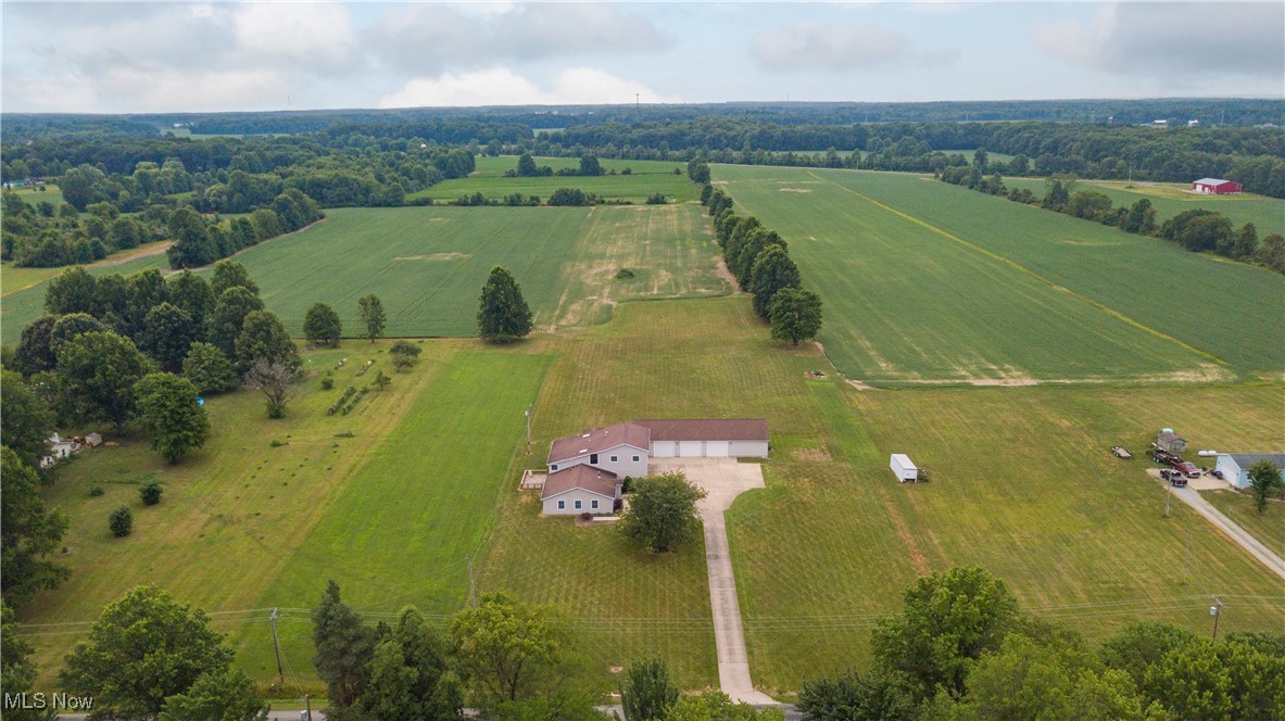 Set on over 9 acres of scenic countryside, this 4,900 sq. ft. Colonial home offers not only spacious, elegant living but also exceptional outbuildings, including a heated 40x80 structure with 12x11 garage doors, ceiling fans, and ample room for equipment, vehicles, or a workshop, plus a generous 39x24 three-car attached garage. Inside, the home features five bedrooms and 2.5 baths, blending classic design with modern amenities. The inviting living room with a gas fireplace leads to an expansive kitchen with a breakfast bar, quality appliances, and access to a deck overlooking the tranquil landscape. A first-floor bedroom and half bath offer convenience for guests or multigenerational living, while a dedicated office provides quiet workspace. Upstairs, a large great room and four additional bedrooms include a luxurious primary suite with a two-level layout, two-sided fireplace, full bath, and private hot tub room. Commercial-grade mechanicals, including an oversized hot water tank, ensure lasting efficiency in this rare blend of timeless charm, practical functionality, and serene rural setting.
