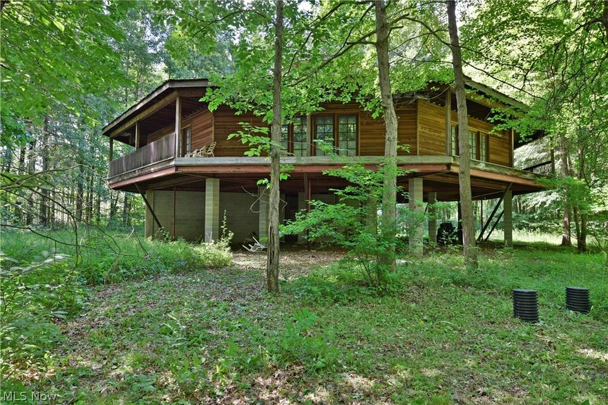 Beautifully elusive shielded in natural privacy one-of-a-kind treetop getaway is not finished just waiting for you to unleash its full potential. A tree lined property and architectural  delight is a unique raised octagon open central second floor layout that brings in natural lighted scenic views from 8  angles. An engineering marvel designed I-beam supported structure  with a block sub layer designed to be lower garage space with three entries at basement level. The main floor showcases tall  pillars  designed to wrap an exposed central fireplace with a chimney extending next to a spiral staircase that passes through the third-floor loft and natural lookout. Redwood doors have with stood the test of time. The deck space provides a wraparound patio. Framework shows three bedrooms with massive master suite with bath and closets. Adjacently a 48' x 60' garage serves as finished shop space complete with a kitchenette, bath, 150 amp service,radiant propane heat, front and back insulated 1