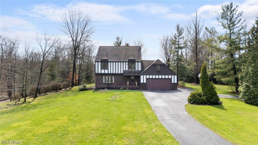 Munson Twp....Spacious Tudor-style Colonial set back on 2+Private Acres! This warm and inviting home offers incredible living space with over 3000 finished sqft, 5 Bedrooms, 3.5 Baths, full basement with plenty of room to grow! Main level living includes traditional floor plan with foyer entry, Formal Living and Dining Rooms, Eat-in Kitchen with all appliances & dining area. Great Room with vaulted/beamed ceilings, wood burning brick fireplace, built-in bar & bookcases and patio access. Huge 2nd floor Loft/Bonus Room overlooks Great Room below. 4 Bedrooms on 2nd level includes Master Bedroom Suite with walk-in closet & Master Bath. Full guest bath with double sink vanity. Step up to the 3rd level Bonus Room with private 5th Bedroom and full bath...this space is ideal for teens or guest suite! Full partially finished basement w/utility/storage room. 1st floor laundry room & updated half bath. New water softener/filtration system. 2+car attached garage with EV charger & paved circular driveway. Enjoy peaceful wooded views this summer from the expansive patio overlooking nicely landscaped yard with spring/creek & storage shed. This home is ready for your growing family to make memories of their own! Close to shopping, restaurants, parks, schools and just minutes to freeway access! 1-yr Home Warranty. Chardon Schools.