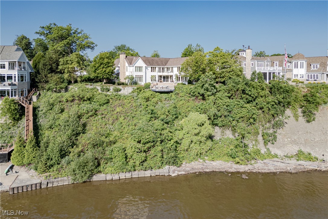 Welcome to 19486 Frazier Dr, an architectural masterpiece custom-built in 2008. This 8,600 sq. ft. luxury home blends impeccable craftsmanship with breathtaking panoramic views of Lake Erie and the Rocky River. Situated just a short walk from the Cleveland Yacht Club, Rocky River Park, and the vibrant Old River District, this rare opportunity offers the perfect combination of elegant design and stunning surroundings. The grand foyer, with its sweeping staircase, sets the tone for this home’s refined ambiance. Designed for both intimate gatherings and grand entertaining, the main level boasts two expansive living rooms, a formal dining room, and two fireplaces, all framed by floor-to-ceiling windows showcasing mesmerizing water views. The gourmet kitchen features Miele and Bosch appliances, quartz countertops, custom white oak quarter sawn cabinetry, and a hand-finished tile backsplash. A full scullery and first-floor laundry offer added convenience. A private office with a gas fireplace opens to a limestone patio with a wood-burning outdoor fireplace. The main floor also includes a guest suite, elevator, mudroom, and a stylish half bath with a custom quartzite vanity. Upstairs, two potential primary suites each boast a fireplace, spa-like ensuite bath with Calacatta marble, and generous walk-in closets. Two additional bedrooms with a kitchenette and full bath complete the upper level. Two limestone patios upstairs offer an outdoor fireplace and sweeping lake views. The fully finished lower level includes a gym, rec space, kitchenette, and full bath. Additional features include six interior fireplaces, two outdoor fireplaces, five patios, white oak floors, Rohl and Waterworks fixtures, and a heated 3-car garage. This exquisite property offers the pinnacle of lakeside luxury, blending opulence with natural beauty.