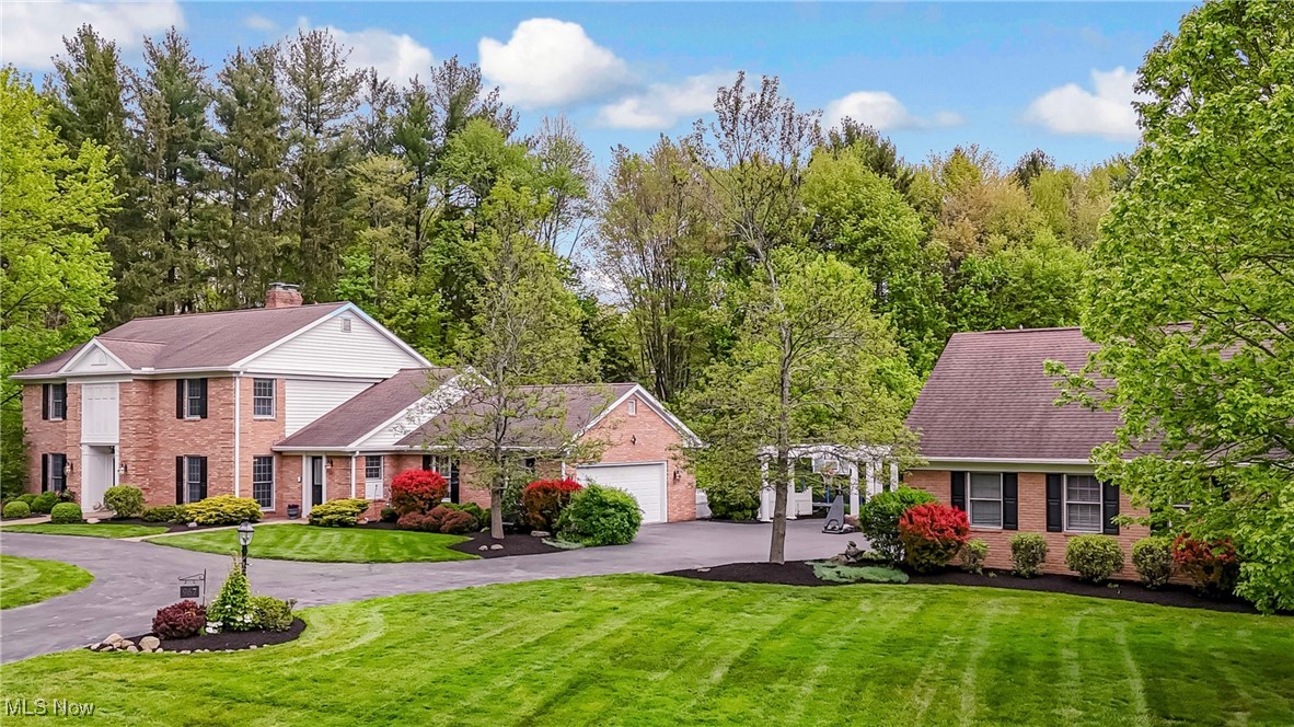 This impressive 7-bedroom center hall colonial offers over 4,400 sq ft of above-grade living, set on a private 1.36-acre lot in sought-after Bath Township. Designed for comfort and function, this home features hardwood floors across most of the main level, three fireplaces, a main-floor primary suite with a private sitting room, and a stunning library with custom built-ins and fireplace. Upstairs, you will find four additional bedrooms, including a second primary suite—ideal for multi-generational living or guests. The walk-out lower level adds 1,800+ sq ft of finished space including a 2-bedroom, full bath in-law suite and direct access to a secluded patio. The large yard feels like a private retreat, surrounded by mature trees and established landscaping. Parking and storage are abundant, with an attached, heated two-car garage and a separate heated, two-car garage that includes a large, unfinished upper level—perfect for a home office, studio, or future expansion. A rare blend of size, versatility, and timeless charm in one of the area’s most desirable locations!