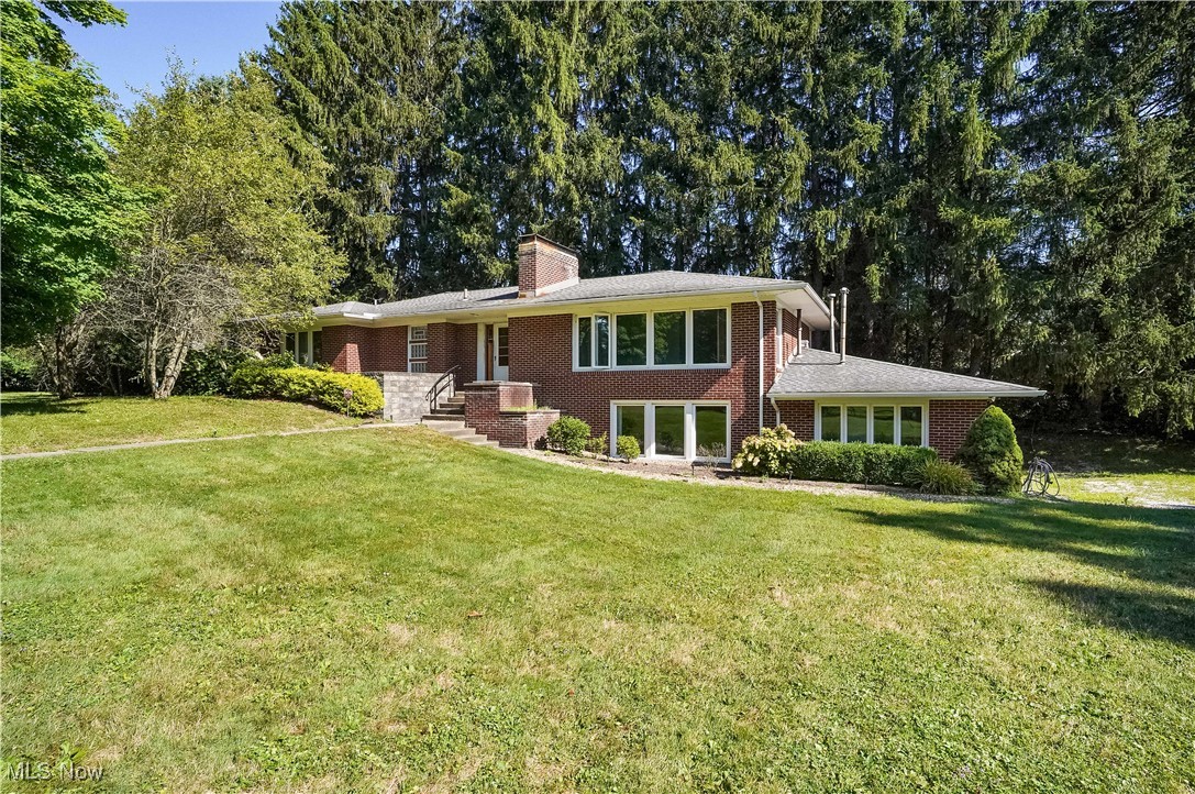 Nestled between Avalon at Squaw Creek Golf Course and the beautiful Creekside development, there is a fabulous property with a tree lined driveway that leads to a private retreat nestled on 2.5 acres! This custom created brick, raised-ranch was built by a mason, thus built by the finest contractor standards with block walls through out. The Big Bad Wolf is not blowing this house down! The main floor has 3 bedrooms, eat-in kitchen, dining room and a large living room with a charming fireplace, along with a wall of windows with views of the golf course and the serene yard. The walk-out lower level was built for in-law or multi-generational purposes with a bedroom, laundry room, bathroom, and another fireplaced family room. This raised ranch provides another open wall of windows in the lower family room, adding wonderful natural lit finished living space to this flex space. The extra deep attached garage provides many possibilities such as a workshop and enters into the lower level. Additional highlights include city water and city sewer tied in around 2018. In 2013 and 2014 the kitchen was updated and electric was expanded. Around 2010 the windows, roof and gutters were replaced and the hot water tank replaced around 2022. Heat is gas radiant with the heating in the floors mostly. Located minutes to the Youngstown Warren Regional Airport, shops, dining, recreation, golf and tennis, this home offers exceptional convenience. Create equity with some finishing touches and turn this into a modern beauty. See the link above for the 3D self guided tour! Sqft numbers come from the floor plans and includes the upper and lower areas that are above ground.