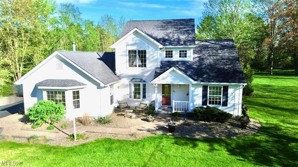 Experience year-round enjoyment at Roaming Shores in this charming colonial home, set on a spacious double lot. Enjoy easy access to the lake, clubhouse, main beach, community docks, tennis/pickleball courts, swimming pool, playground, and more—all without needing to drive. A convenient path at the property’s northern edge leads directly to over 10 acres of community land! The additional lot offers ample parking for boats, RVs, or large vehicles, and could also provide space to expand with another home or garage if desired. This home boasts a fantastic outdoor living area with a lush, expansive lawn and a circle of mature trees, creating a private and peaceful setting. Step inside to a striking two-story foyer featuring tile floors and a cozy wood-burning stove, perfect for relaxing by the large bay window. French doors open into a spacious great room with hardwood floors, multiple windows offering natural light from three sides, and a wood burning fireplace, making it an ideal space for entertaining. The eat-in kitchen features white cabinetry, quartz countertops, and stainless steel appliances. It flows seamlessly into a covered pavilion, perfect for outdoor dining and relaxation. The first floor also includes two bedrooms, a full bathroom, a laundry area, and additional attic storage. Upstairs, the primary suite is a true retreat, with a vaulted ceiling, skylights, and an en-suite bath. A fourth bedroom is also located on the second floor. The home includes a large, attached two-car garage and plenty of additional storage space. Located in a prime spot within Roaming Shores, this home is just a short drive to the grocery store, marina, gas stations, dining, and more. The home has been meticulously maintained, with a new roof and heat pump installed in 2023, and windows replaced within the last 10 years. It’s also wired for a whole-home generator. Move in and start enjoying all the fantastic amenities that the Roaming Shores community has to offer.