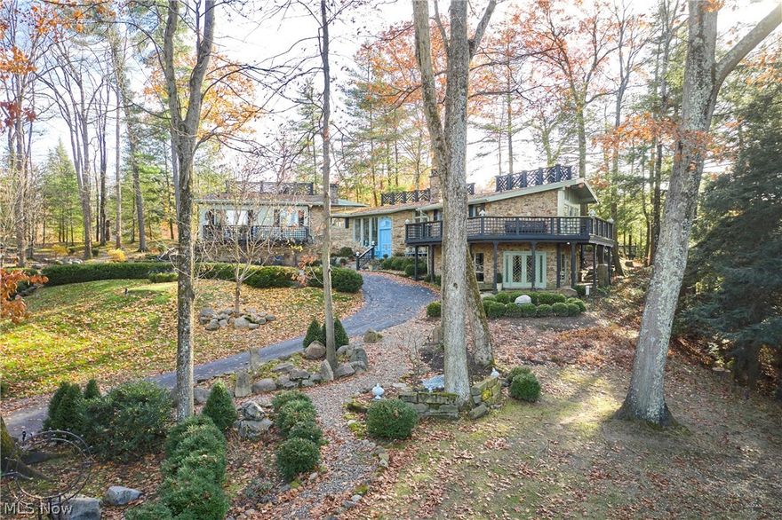 A rarified offering in Revere Schools, this nearly 11-acre hilltop estate is defined by privacy, natural beauty, and possibility. Set along a private drive, the property unfolds across open ground, mature trees, varied topography, and gorgeous long views, with the peaceful sounds of the nearby creek, creating a setting that feels both secluded and extraordinary. The changing elevation adds dimension and character throughout the landscape, while wooded edges frame the property beautifully and enhance the sense of serenity. The residence is a masterclass in organic architecture, where stone, glass, and natural light are not simply materials, but the language of the home. Thoughtfully maintained and extensively renovated since 2005, including mechanical systems, the home reflects a long-term commitment to quality and care. A welcoming foyer introduces open-concept living and dining spaces that flow seamlessly to expansive terraces, inviting the outdoors in. The kitchen and great room are designed for everyday ease, generous in scale, exceptionally well-appointed, and offering abundant storage. A thoughtfully designed split-bedroom layout provides both privacy and flexibility, with a primary suite and adjoining office or fifth bedroom set apart from three additional bedrooms on the opposite wing. Custom millwork, richly layered interiors, and carefully proportioned rooms support both intimate living and refined entertaining, while each space feels distinct in character yet harmoniously connected. Outdoors, the experience is equally compelling. Meticulously maintained grounds, winding paths, curated gathering spaces, and a beautifully sited observation deck are positioned to take full advantage of the property’s elevation, long views, and peaceful natural setting. This is not simply a home, but a composition—carefully sited, beautifully executed, and nearly impossible to replicate.