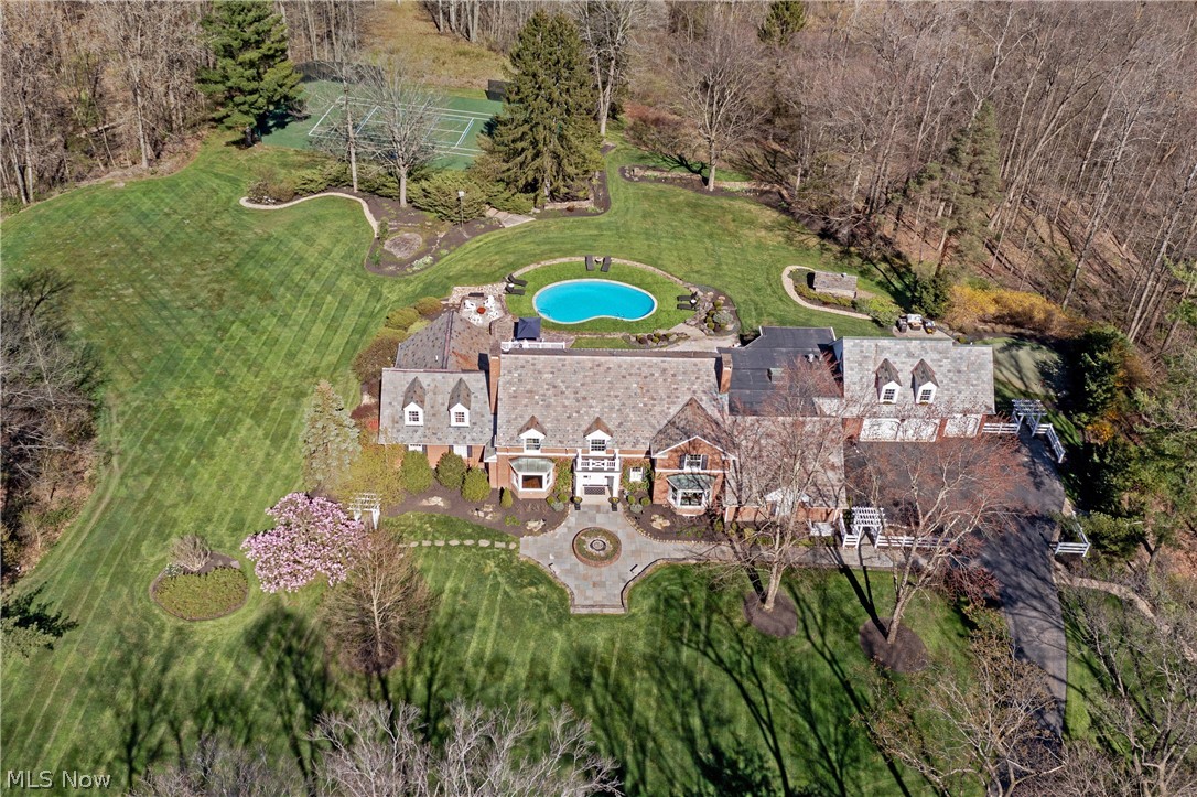 Tucked away amongst the rolling countryside of Daisy Hill, this pristine estate rests on nearly nine acres of impeccably manicured grounds in the heart of Hunting Valley. A masterful blend of classic and contemporary architecture, this home has been expertly renovated with award-winning design, and is perfectly positioned to capture the spectacular Chagrin Valley views from almost every room. Every element of this home is practically perfect in every way: from the slate roof to the English-style pub, from the pool to the tennis court and practice green, the thoughtfulness of design both inside and out, cannot be overstated. Upon entry, dark hardwood floors are offset by crisp white molding and a dramatic curved staircase, immediately creating the air of understated elegance that pervades the home. To the left and right, the formal living and dining areas include charming features designed for both comfort and convenience, including a cozy window seat with a recessed bookshelf, two fireplaces, and a butler’s pantry complete with a sink and beverage fridge. The spectacular eat-in kitchen boasts custom white cabinets, marble counters and Wolf range with egress out to the multiple outdoor terraced patios and screened in porch. Adjacent to the kitchen is the family room, offering up a wonderful sense of peace and tranquility with walls of windows bringing the outdoors in. A sitting area and coffee bar are tucked away with a private seat from which to survey the landscaped backyard and rolling valley beyond. Off the side entrance and formal powder room, a private stair takes you to an office with a vaulted ceiling. On the opposite end, the first floor primary is sequestered by itself, complete with two walk-in closets, vanity area and coffee bar, and a luxurious marble en-suite with glass step-in shower and soaking tub. Three expansive bedroom suites with private baths are found on the second floor, one complete with lounge and private terrace.