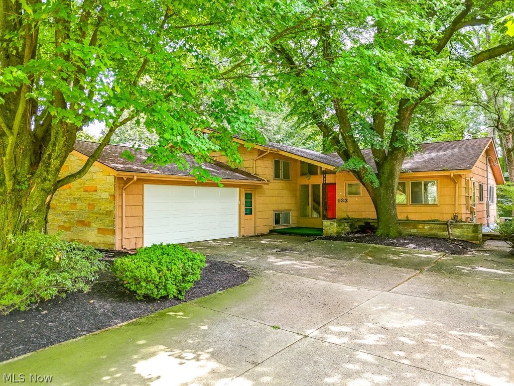 Location! Location! Location! Situated in the highly sought-after University Heights neighborhood, this spacious mid-century split level offers an impressive 6 bedrooms and 3.5 baths, providing plenty of room for ALL your needs. While some updates are needed, with a little work, this property is full of potential to become your ideal home in an ideal location. The main level features a living and dining room combo with a cozy wood burning fireplace and is wrapped in a WALL of windows, inviting natural light and blending indoor and outdoor spaces beautifully. The original eat-in kitchen boasts ample cabinet space, including a workstation, plus all appliances. A convenient powder room is also located on the main level. Upstairs, are three bedrooms all with ample closet space and a full shared bath, plus a primary suite with an en-suite bath with a separate makeup bureau. The lower level offers two additional bedrooms and a 3rd full bathroom, as well as a spacious recreation room with a slider leading to an enclosed brick patio that provides over 200 square feet of additional outdoor living space. Adjacent to the recreation room is a laundry room equipped with a utility sink, washer and dryer, and refrigerator, as well as a convenient walk-out to the private and flat backyard surrounded by lush mature trees and freshly landscaped flower beds. The partial basement offers abundant storage space as well as potential for additional living space - not that you need it! You'll appreciate the newer A/C, roof, and garage door (all within the last 6 years) and new electric panel (2024). Enjoy ample parking from the oversized 2-car garage and extended driveway. This PRIME location is across Main Street from Kent State and just minutes from downtown Kent's vibrant shopping and dining scene. Don’t miss this opportunity to bring your vision to life at 123 Overlook Drive. Schedule a viewing today!