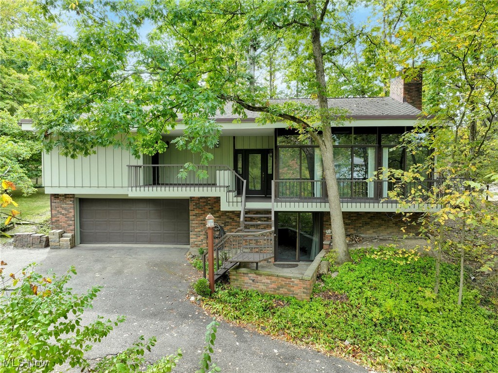 Nestled in a beautiful wooded setting, this custom-designed modern home blends contemporary comfort with the tranquility of a natural retreat. Custom designed with an abundance of windows throughout, the home invites natural light into every room and allows you to enjoy the picturesque setting from nearly every angle. The floorplan features three bedrooms and two-and-a-half baths with two spacious living areas. At the center of the home is a spacious kitchen, ideal for both cooking and entertaining. Highlights include a large center island, Corian countertops, and custom wood cabinetry offering exceptional storage. The adjoining eating area is a true delight—surrounded by windows, it creates the perfect spot to enjoy morning coffee while overlooking the peaceful landscape. The primary suite has deck access and boasts two closets and an updated bath with a tile shower. Two additional generously sized bedrooms share a hall bath. On the walkout lower level, a welcoming family room with a wood-burning fireplace sets the stage for cozy evenings, while laundry facilities and direct garage access add everyday convenience. Outdoor enthusiasts will appreciate the property’s unique features, including a charming pond, a detached garage, and a dedicated RV parking pad complete with hookup—perfect for adventure seekers. The exterior has been freshly painted. Blending the warmth of a cabin in the woods with the conveniences of modern design, this Walton Hills gem offers the best of both worlds: serenity, style, and accessibility. Whether you’re seeking a year-round residence or a private retreat, this property is a rare find in a desirable location.