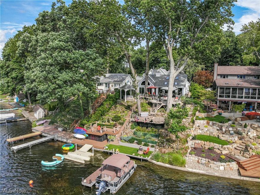 This award-winning Portage Lakes home faces west to offer spectacular views of the lakes, sunsets, and fireworks. Have your choice of views from the Multi-level decks overlooking the water, relax in the hot tub under a gazebo just steps away from the master suite, or sit around the fire and listen to the water feature as boats pass by. You also get a double boat dock and kayak/paddleboard launching deck with storage. Don’t let the size of this home fool you, it lives like a ranch but has the capacity to host friends and family with ease. The main level includes a gourmet eat-in kitchen with granite countertops, a center island with a vegetable sink, and top-of-the-line stainless appliances. Off the kitchen, the great room has shiplap vaulted ceilings with panoramic views of the water. Off the hall, double doors lead to the master retreat with a 2 sided fireplace and access to the enclosed sunroom from french doors. HUGE master bath with a tiled walk-in shower and jetted tub with access