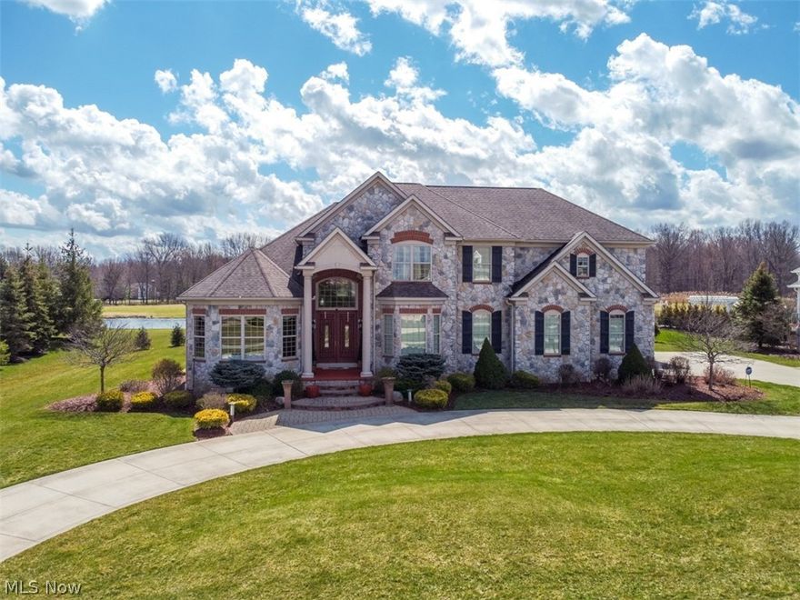 Welcome to this stunning custom-built Prestige Home in the Canterbury on the Lakes neighborhood. From the perfectly manicured yard w/12 zone sprinkler system, the circular driveway, a full stone exterior, rear covered porch with lake views, central sound system, and dual gas lines for an outdoor fire pit and gas grill, this home is meant to enjoy the outdoors, but the interior is an entertainer’s dream! The first floor has much to offer from the 4-car garage, spacious mud/laundry room with an abundance of storage, study with built-in shelves, formal dining room, two-story foyer, and a wide-open floor plan. This home boasts a chef’s kitchen including a large island w/seating, 5/burner gas range, double ovens, built-in microwave, and walk-in pantry.  The great room has vaulted ceilings, a wall of windows for an abundance of natural light, and a cozy stone fireplace.  A first-floor master suite with views of the lake, a dreamy walk-in closet designed by California Closets, a glamorous mas