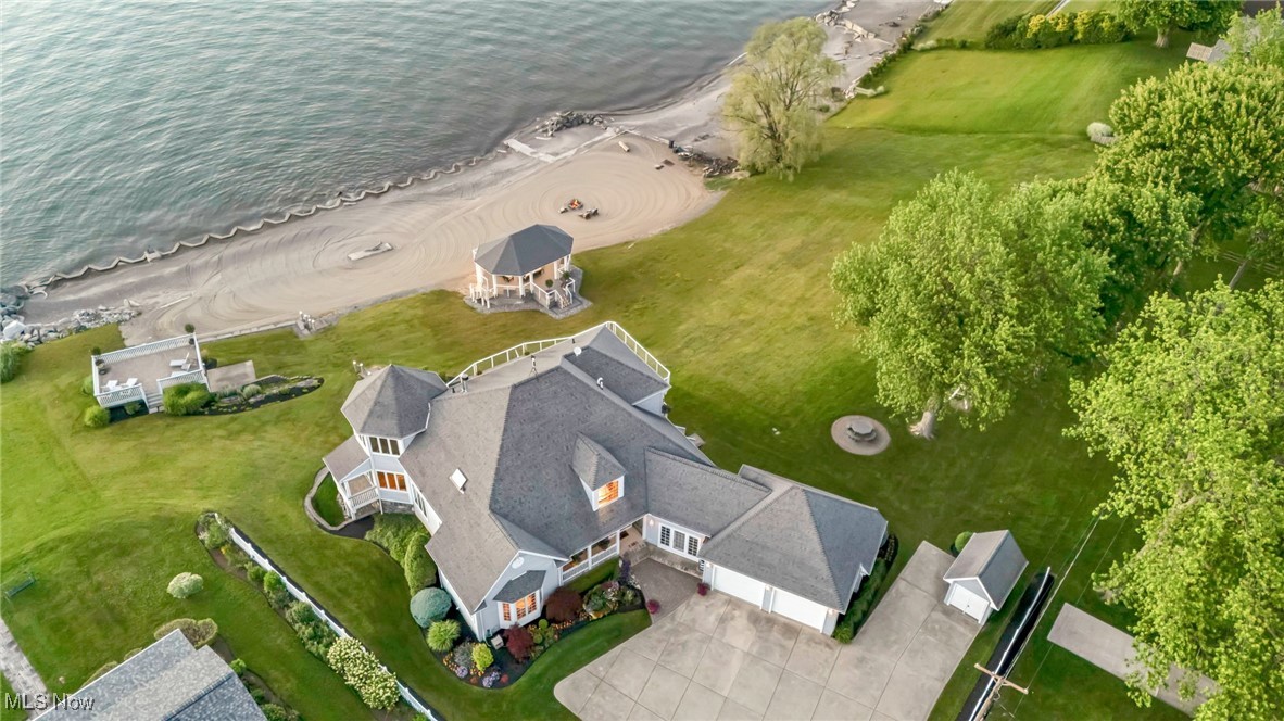For the one who refuses to settle. This is not just a lakefront home, it’s a once-in-a-lifetime opportunity to own one of the largest private sandy beaches on the east side of Cleveland. Tucked on over 2 pristine acres encompassing 3 parcels with one buildable stand alone, this custom 3-story estate isn’t just rare, it’s irreplaceable. Designed for the bold, the accomplished, and the generational thinker. This architectural showpiece offers uninterrupted Lake Erie views, soaring ceilings, and over 6160 s.f. of luxury crafted for indoor-outdoor living at its finest. It’s the kind of property that doesn’t come around twice. From the wraparound porch to the rooftop boathouse lounge with all toy storage below, covered two story pavilion, and private beachfront fire table, every inch is designed for elevated lakefront living. Inside, soaring ceilings and walls of glass frame endless water views. The chef’s kitchen features granite and quartz surfaces, custom cabinetry, a built-in double oven, and a walk-in pantry. Multiple fireplaces throughout, including the great room, lower level, primary suite, and guest house, bring warmth and intimacy to this expansive layout. A Lutron Caséta lighting system sets the mood at the touch of a button, while a Sonos whole-home sound system fills the air with music in every space. The walk-out lower level adds a guest suite, additional wet bar with dual beverage coolers (250+ bottles), gym, and woodworking studio, all with direct patio access. Main home attached garages, plus an additional 3-car detached garage with a full 2 bedroom guest house above, offer room for everything and everyone. Extensive shoreline protection in place, including a professionally engineered break wall for long-term erosion control. This investment ensures beach integrity, property stability, and year-round enjoyment. Quietly luxurious and unapologetically rare, this is where the lakefront dreams live boldly.