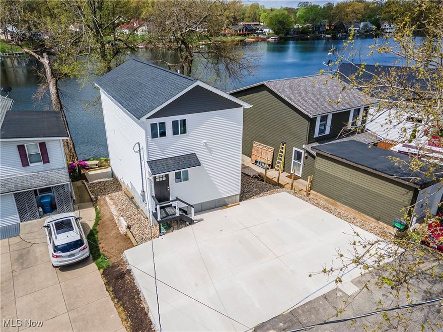 Welcome to this stunning 2025 new build on the north end of the West Reservoir in Portage Lakes—where sleek modern design meets laid-back lakefront living. With 4 bedrooms, 3.5 bathrooms, 5 parking spaces, and a private dock with two boat slips, this home delivers the full lake life experience. The main level features an open-concept kitchen and living space with panoramic water views and direct walkout access to a spacious lake-level deck and patio, perfect for entertaining or relaxing by the shoreline. Inside, you'll find granite countertops, white shaker cabinets, stainless steel appliances, and luxury vinyl plank flooring throughout. Upstairs, both bedrooms have private full en-suite bathrooms, offering comfort and privacy for guests or family, along with a conveniently located laundry room. On the top floor, the vaulted-ceiling owner’s suite offers a serene retreat with a private balcony, oversized walk-in closet, and a spa-like en-suite bath with dual sinks and a tiled walk-in shower. A fourth bedroom or flex space completes the third level. Enjoy maintenance-free composite decks on both upper levels as well as a concrete patio on the lower level, all designed to maximize views and minimize upkeep. Whether you’re boating to dinner, hosting sunset happy hours, or just soaking in the view with coffee in hand, this home offers a rare chance to own new construction with direct water access in a coveted location. Move-in ready and built for the good life—schedule your private tour today.