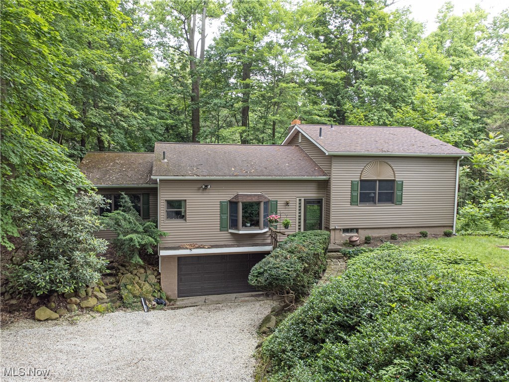 Tucked away on nearly an acre overlooking the gorge in beautiful Stow, this one-of-a-kind home feels like a private retreat. Nestled down a long driveway and surrounded by natural stone landscaping, you'll be captivated before you even step inside. As you enter, the warm hardwood floors, thoughtfully designed layout, and abundant windows showcasing breathtaking views immediately welcome you in. The spacious kitchen is a dream for cooks and entertainers alike, featuring granite countertops, a double oven, and a picturesque corner sink that perfectly frames the view. The living room, with new carpet (June 2025), boasts a stunning stone fireplace and seamlessly flows into the oversized dining area, both filled with natural light and hardwood charm. Just off the dining room is a large bonus room or office with direct access to a serene back deck, perfect for soaking in the peaceful surroundings. Upstairs, you'll find three distinctive bedrooms, including a truly special owner's suite with a private balcony. It feels like a calming treehouse hideaway, ideal for slow mornings or stargazing nights. A full bathroom with a stunning wood ceiling feature finishes off the first floor. The finished lower level offers even more living space, complete with a cozy second fireplace, a full bath, and a unique Jacuzzi room for your own spa-like escape. A walk-out patio provides yet another vantage point to enjoy the stunning gorge views. Down a few more steps, you'll find the laundry area, additional storage, and access to the two-car garage with extra storage space for all of your tools and toys! This home is currently on well water, but public water is available at the street if desired. With only two owners, this lovingly maintained home is ready for its next chapter. Private yet close to all of Stow's amenities, it offers the perfect balance of convenience and seclusion. If you're seeking a home that feels like a getaway every day, this is the one.
