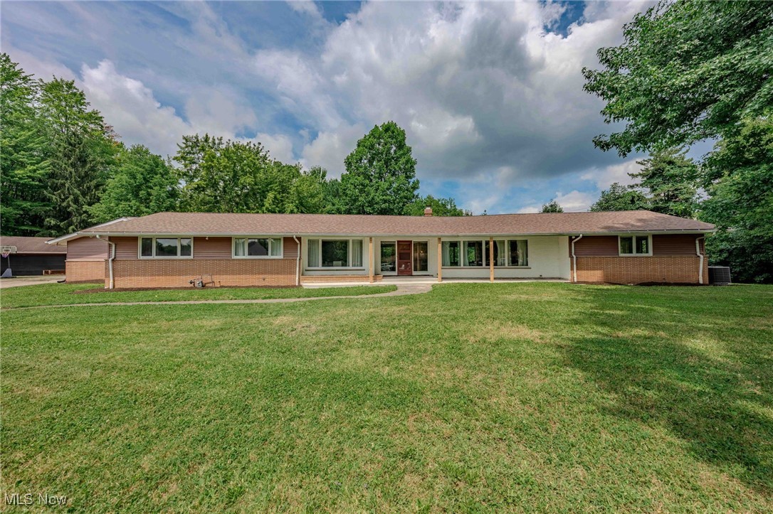 Bring your vision to this one-of-a-kind mid-century modern ranch, nestled on 1.6 wooded acres in Broadview Heights. With 4 bedrooms, and 3.5 baths this home is full of timeless character and exciting potential. The living room makes a strong impression with a large stone-faced fireplace and plenty of natural light from oversized windows that frame peaceful wooded views. The retro kitchen blends form and function with vintage turquoise countertops, a copper range hood, Sub-Zero fridge and freezer, and opens to a cozy family room with beamed ceilings and a second fireplace. Sliding glass doors from the kitchen and family room lead to a spacious patio, creating a seamless indoor-outdoor flow perfect for entertaining or relaxing amid the serene wooded backdrop. The private primary bedroom offers sliding glass doors that lead directly to the backyard and an en-suite bath with granite counters and a dramatic stone-wrapped soaking tub. Three additional well-sized bedrooms provide comfortable space for family, guests, or flexible use as an office or hobby room. The lower level adds more opportunity with a rich, wood-paneled bar that brings warmth and character, along with ample unfinished area perfect for a home gym, workshop, or storage. Car lovers and hobbyists will appreciate the attached 3-car garage and oversized 4-car detached garage, ideal for tools, projects, or recreational gear. Located at the end of a quiet cul-de-sac and surrounded by beautiful new builds, this property offers a rare opportunity to reimagine a mid-century classic in a setting that feels both private and full of possibility.