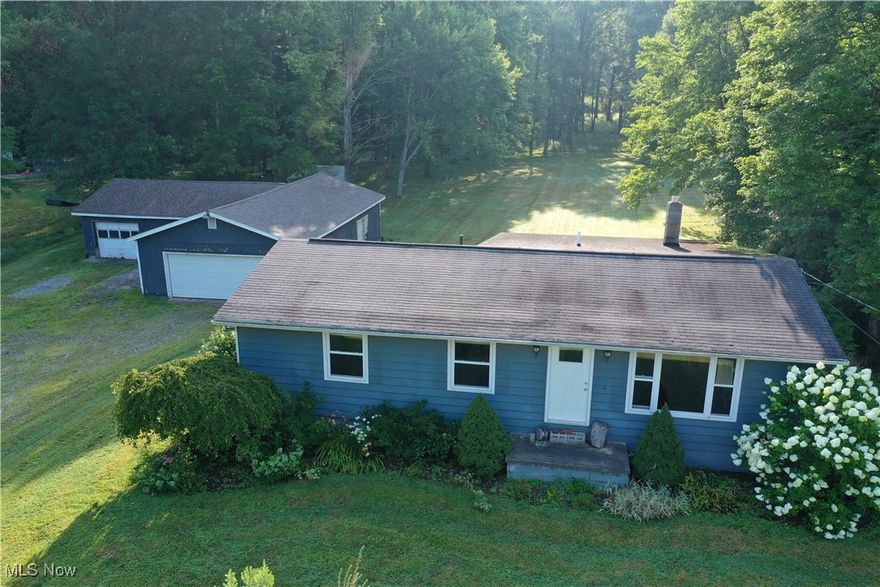 This 25+/- acre property offers a balanced mix of residential living, outdoor recreation, and wildlife potential. Tucked into a quiet setting with access via a maintained road, the land presents an opportunity for those seeking space for hunting, hobby farming, or outdoor enjoyment. The terrain is a combination of open yard space, wooded cover, and a scenic pond, which all contribute to the property's wildlife habitat and recreational value.

The ranch-style home features three bedrooms, an updated kitchen, and a full unfinished basement that adds additional space for storage or future use. The layout is functional and provides all the essentials for daily living. Utility connections are in place, offering electric service, plumbing, and heating.

Adjacent to the home is a large detached garage/outbuilding that provides substantial storage for equipment, vehicles, or recreational gear. The surrounding yard is expansive and offers open space that can be used for gatherings, outdoor projects, or simply enjoying the rural setting. The backyard flows into the wooded acreage, which contains excellent deer sign and natural cover—key features for those interested in hunting or wildlife observation. Additionally, the property adjoins the Western Reserve Greenway Trail. 

The pond is both a visual and practical feature of the property, adding to the habitat diversity and potential for fishing or livestock watering if desired. Access throughout the acreage is manageable, with gently rolling topography and trails that could be developed or maintained.

Buyers seeking a rural lifestyle, space for outdoor activities, and the convenience of an on-site residence with utility access will appreciate the value this property offers. The blend of woods, water, and open space supports multiple uses, from weekend retreats to year-round living.