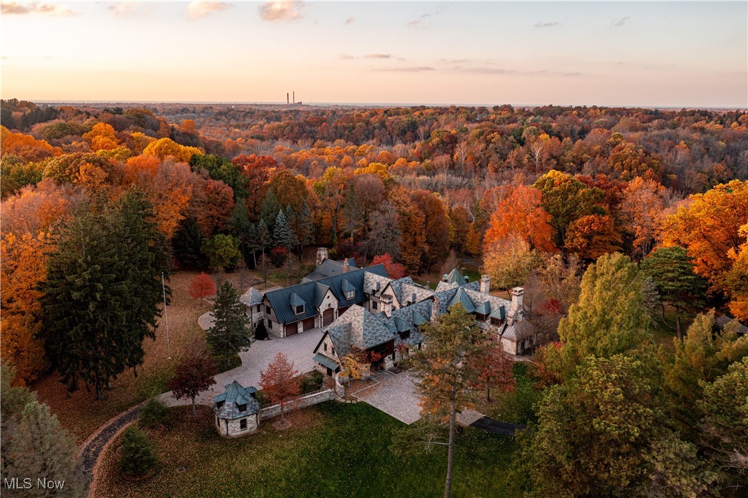 Situated on over 14 acres overlooking the Chagrin River Valley, this exceptional chalet provides the epitome of distinguished living in an unmatched natural setting. Originally designed by Tony Paskevich, this magnificent manse is an architectural triumph with astonishing details and over 12,000 square feet of living space. The property is complete with every possible amenity catering to every possible desire, from a two-lane professional bowling alley to a private ski slope wired for your own chair lift. Beautifully set back from the road by a gated drive, the front entrance is evocative of a romantic fairy tale. A cobblestone paved porte cochere and motor court wrap the property and provide multiple points of entry into the main residence. The front door beckons with stained glass accent windows and opens to the dramatic great room and kitchen. Two stone fireplaces and large windows frame both spaces. The entertaining wing includes a spectacular vaulted game room which opens to the two-lane bowling alley and lounge with a full kitchen. Step out to the multi-level stone terrace to enjoy multiple outdoor fireplaces, full court basketball court, or the exceptional serenity of the beautifully wooded setting. Six bedroom suites can be found on the second floor, including an exceptional owner’s suite. The 5 car tiled garage is heated with custom 10’ solid chestnut doors and a complete guest apartment upstairs. This estate is truly a trophy property for the most discerning buyer.