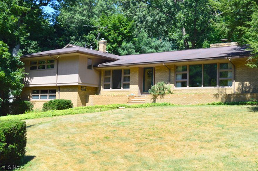 An amazing, Mid-Century  Modern style home tucked away in the quiet Nob Hill neighborhood of West Akron.  The home offers over 2800 Sq. Ft. with many desirable original features and many updates.  Off the front foyer is a two story, 25 x 18' Great room with walls of large windows letting in the sun and exposing the beautiful views.  Attached to the great room is the formal dining room- both sharing the warmth of the corner fireplace.   Off the other side of the foyer is an 18x14' Family room with hand-rubbed, Walnut paneling and bar, spacious kitchen with newer appliances, granite counter tops, half bath, first floor laundry and the door to the back yard with a private, park-like setting & patio.   Just a few steps below the family room is the attached 2+ car garage, a 20x15' Bonus room (or office) with separate entrance, the furnace room and a full bathroom.  Just a few steps above the main level are the 4 bedrooms and 2 full baths- one off the hall, one in the master bedroom.   The M