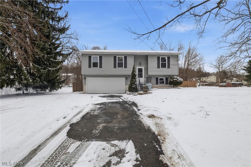 This well-maintained bi-level home offers the perfect blend of space, updates, and outdoor living. Step inside to a spacious open-concept main level featuring modern vinyl plank flooring that flows seamlessly from the generous living area into the updated kitchen. The kitchen is a true highlight, boasting crisp white cabinetry, a full suite of stainless steel appliances including an LG French door refrigerator with water and ice dispenser, gas range, built-in microwave, and dishwasher, plus a movable center island for added prep space and storage. A stylish ceiling fan and abundant natural light complete the inviting atmosphere. The dining area is perfectly positioned beside sliding glass doors that open to a large deck with modern white and black aluminum railing -- ideal for morning coffee or evening entertaining with scenic views of mature trees and the surrounding landscape. The upper level features three comfortable bedrooms, each with plush carpeting and ceiling fans. Bedrooms include ample closet space with sliding panel doors. The full bathroom offers a tub/shower combination, a handsome wood-framed medicine cabinet with vanity, and a skylight that fills the room with natural light. The finished lower level delivers valuable bonus living space -- a large family room with fresh paint, new carpet, and multiple storage closets, perfect for a recreation room, home office, or playroom. A convenient half bath on this level adds everyday functionality. The utility room houses the water heater, furnace, and a laundry tub for added convenience. Outside, the oversized fully fenced backyard provides privacy and plenty of room for kids, pets, gardening, or future entertaining. A storage shed and swing set area add even more appeal. The attached two-car garage with automatic opener and wide driveway offer generous parking and storage. Don't miss this move-in ready home with the space and features today's buyers are looking for.