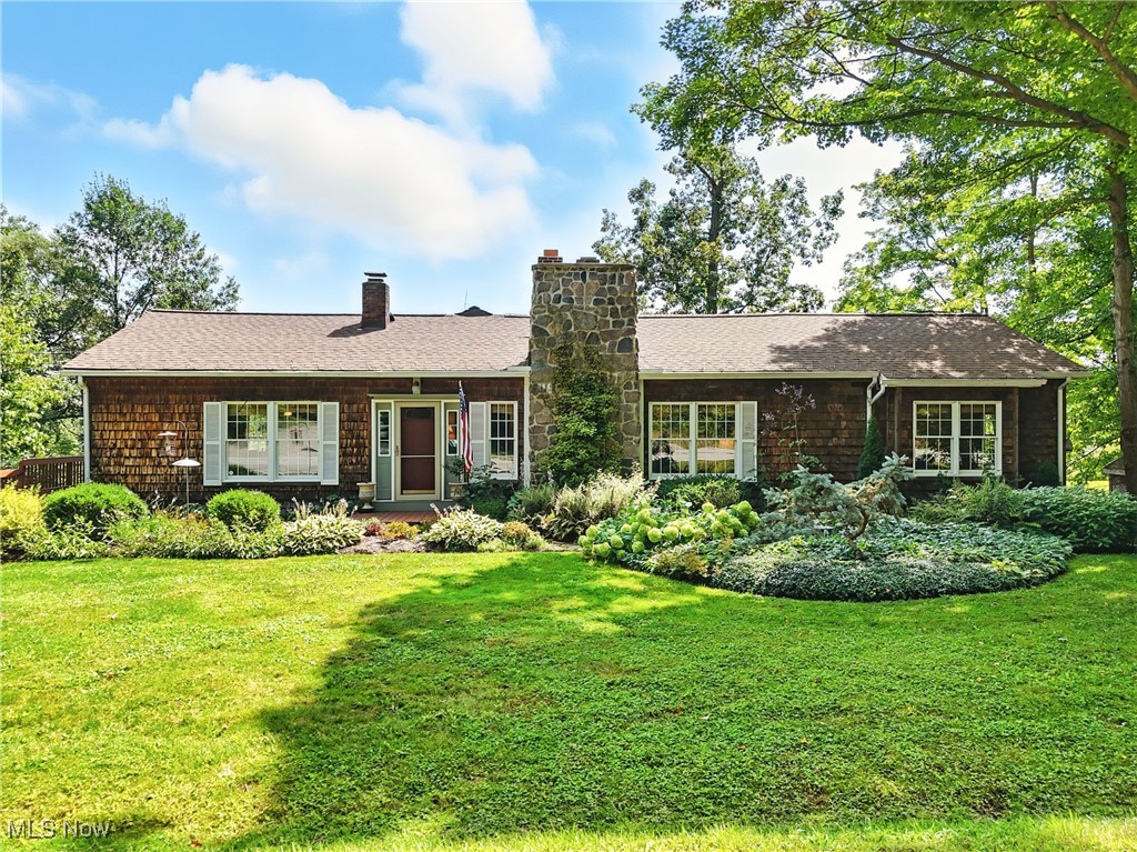 This breathtaking cedar-sided ranch in Chardon sits on just over 3 acres across two parcels and has been lovingly maintained and thoughtfully updated by its original owners for over 40 years. The three-bedroom, two-bath home welcomes you with warm wood floors that lead into a bright living area, while the spacious kitchen features double islands—one with butcher block—stainless steel appliances, and a cozy breakfast nook with an original stone oven. The great room offers sweeping views of the scenic back property and direct access to a large deck perfect for relaxing or entertaining. A stunning owner’s suite addition includes soaring ceilings, expansive windows, private deck access, and a spacious en suite bath with dual countertops and a dedicated vanity area. Two additional bedrooms share a well-appointed hall bath. All seasons can be enjoyed on the second-story deck while taking in panoramic views of the two parcels. A custom-made bridge leads to a private fire pit area, ideal for relaxing or entertaining, while a thoughtfully designed potting island sits on the side of the home. A side door opens into the garage, with access to the home via a flight of stairs. Recent updates include a new roof (2022), furnace and AC (2020). With calming spaces both inside and out, this beautifully cared-for home offers peaceful living just minutes from shops, restaurants, and all the charm of Chardon.