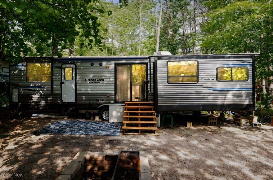 Own a slice of paradise in Hocking Hills with this well-appointed 32' 2019 Coachman Catalina Destination Series, perfectly situated in Lost Hollow Campgrounds. This seasonal retreat comfortably sleeps four adults and includes a king-size bed, fold-out couch, two recliners, a smart TV, and a full-size kitchen with island, dining table, and washer/dryer hookups. Additional features include propane heat, spacious closets, a ceiling fan in the bedroom, and a cell booster for reliable internet. Outside, enjoy your private wooded campsite complete with a firepit, storage shed, and a 2018 Textron EZ-GO RXV golf cart for easy access around the grounds. The automatic awning with LED lighting adds comfort and convenience to your outdoor living space. Lost Hollow offers a wide range of resort-style amenities including two swimming pools, shower houses, laundry facilities, a restaurant, chapel, playgrounds, mini golf, and basketball and tennis courts. With electric, water, and sewage hookups readily available, this turn-key getaway provides the ultimate escape from the hustle and bustle of everyday life. Please note: this is a private, seasonal-use community and rentals are not permitted.