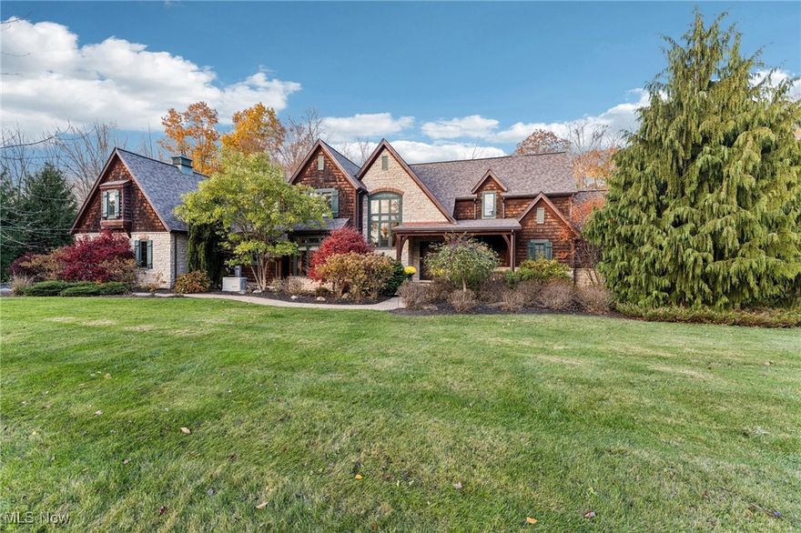 Set on more than 3.5 acres in a breathtaking private setting, this stone and shingle estate blends timeless craftsmanship with modern innovation. With hand-hewn reclaimed beams throughout, rich hardwood, and architectural detailing in every room, this home radiates warmth and sophistication. The vaulted great room features dramatic exposed beams, towering gas log stone fireplace, and custom built-ins that open to a private Trex deck overlooking the property. The gourmet kitchen is a chef’s dream—custom cabinetry, soapstone farmhouse sink, granite countertops, warming drawer, walk-in pantry, and professional-grade Wolf &  Sub-Zero appliances—all connecting to a large open dining area. First-floor primary suite offers private deck access, spa-like bath w/ steam shower, soaking tub, travertine floors, and spacious walk-in closet. The main level also includes an office with custom built-ins, two half baths, large laundry room, and mudroom. Upstairs, find three additional bedrooms—including one that can serve as a second primary suite—and two full baths. The lower level, completed in 2024, is a true showpiece featuring a multi-level, state-of-the-art movie theater with tiered seating, acoustic paneling, and professional-grade sound/projection. A full recreation space with a wet bar, freezer/fridge drawers, stone fireplace, walk-out patio, and custom playroom with a play kitchen make this level an entertainer’s dream. The property offers incredible storage, full workshop, and two separate 2-car garages (both heated)—one of which offers an EV charger and direct basement access. Enjoy evenings on the custom stone patio with firepit, surrounded by mature landscaping and peaceful views. Every inch of this home showcases attention to detail: accent lighting throughout, full smart-home system, Ubiquiti commercial networking, whole-house generator, and refined craftsmanship at every turn. This is a one-of-a-kind residence where old-world charm meets cutting-edge comfort.