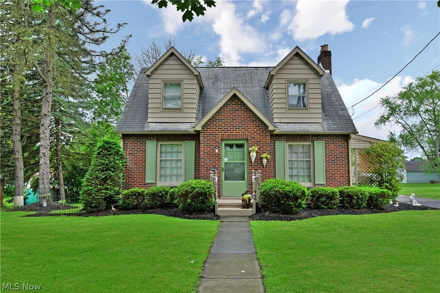 Immerse yourself in the beautiful French countryside without leaving Niles, Ohio! This expertly decorated cape cod illustrates just how appealing it can be! Its handsome red brick construction draws you in as the twin dormer windows peer out over the front yard. Relax in the covered rear patio area or soak up the sun on the large elevated rear deck! Through the dark stained front door, a welcoming living room opens to reveal rich hardwood flooring and a decadent white fireplace. A lattice door provides patio access. Sit down with a meal under the chandelier in the charming formal dining room or explore the cozy kitchen with its ornate lighting and rustic tiled floor. A lovely half bath waits near the rear deck and basement entrances. Upstairs, a trio of gorgeous bedrooms jut off from a full bath and built in cabinets at the top of the landing. A detached one and a half car garage joins a fire pit outside to complete the package.