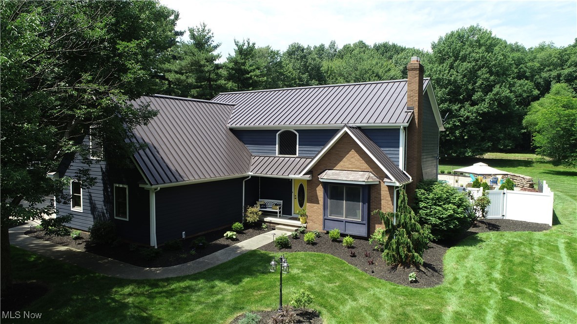 Come home to a beautiful park-like setting on 4 private acres with saltwater pool, hot tub, and pond—perfect for entertaining! Custom-built Colonial features a large family room with new plush carpet. Eat-in kitchen offers granite countertops, island with outlet, walk-in pantry, black stainless appliances, bar with wine and beer fridges, reverse osmosis water system, and new hardwood floors. Panoramic window opens to pool bar for easy outdoor serving. Spacious mudroom with custom cabinets, shoe drawers, and coat storage. Second guest closet off 2-story foyer. Office with French doors overlooks pool—ideal for working from home while watching kids. Gas fireplace in flex dining/living room. First and second floor laundries. Upstairs has 4 bedrooms, 2 full baths. Large primary suite with cathedral ceiling, solar skylights with built-in blinds. Primary bath includes vaulted ceiling, soaking tub, giant tile shower with bench, lighted mirrored double vanity, heated tile floor. Huge walk-in closet fits 150+ shoes, granite island, chandelier, skylight, ironing board, built-in safe. Basement has newly finished rec room with deluxe carpet and vinyl plank flooring, built-in cabinets, large storage room with shelving, multiple closets, and separate workshop with air compressor and 18-ft workbench. Workshop connects to 686 sq. ft. 2.5-car garage with hot/cold water and built-in compressor. 2020 HVAC with humidifier. Upgraded 200 amp panel. Exterior: low-maintenance saltwater concrete pool with tanning ledge, benches, diving board, large deck, hot tub, fire pit, outdoor speakers. Heated 704 sq. ft. outbuilding with loft, workbench, 220 electric, 80-gallon compressor. . In-ground RainBird yard sprinkler system is sourced from well-water. House has city water and sewer. 4 private acres, set-back from road by lighted tree-lined driveway. Secluded yet walkable to all Tallmadge City Schools. Hardie cement siding and metal roof. All appliances stay and furniture negotiable too.