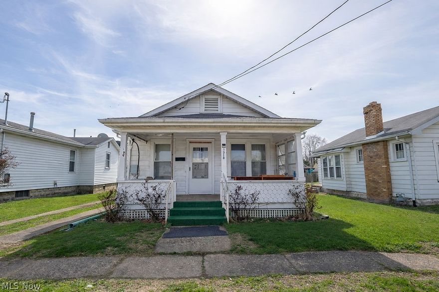 From the moment you arrive, the covered front porch offers a welcoming entry with classic character and a place to pause before heading inside. The living room opens with high ceilings that create an airy feel, while a decorative fireplace adds charm and a natural focal point for gathering or relaxing.

Just off to the right, a flexible room adapts to your needs, ideal for a guest space, home office, or main level laundry to support one floor living. Continue through the living room into a spacious dining area where a large picture window brings in natural light and creates an inviting setting for everyday meals or hosting. Beyond that, a private bedroom connects to the full bath, featuring a step in shower with built in seating.

The kitchen offers generous space with an eat in area, ample counter space, white cabinetry, white appliances, and built in storage to keep everything organized and within reach. From here, a transition area leads you either down to the full unfinished basement with storage or future finishing potential, or out to the backyard.

Outside, the fenced yard provides room to garden, entertain, or unwind, while the detached one car garage with alley access adds everyday convenience. With high ceilings, strong natural light, and a layout full of flexibility, this home presents a solid opportunity to update, personalize, and add value, all while being conveniently positioned with easy access to main routes and everyday amenities.