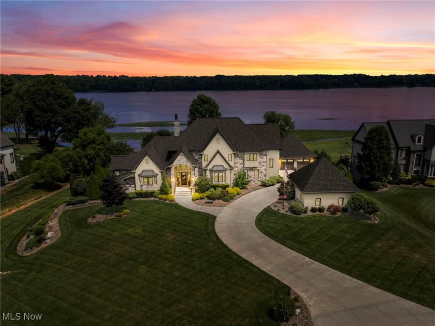 Welcome to this exceptional custom-built lakefront estate in the highly desirable Via Avellino development, located in the coveted South Range School District. Built in 2014 by Master Plan Builders, this architectural masterpiece offers over 4,811 square feet above grade plus an additional living quarters in the finished walkout lower level, combining timeless elegance with modern functionality.

From the moment you arrive, the striking curb appeal, grand gables, stone accents, and manicured landscaping set the tone for what lies within. Step inside to discover a sophisticated interior featuring soaring ceilings, a dramatic 20' floor-to-ceiling stone fireplace and windows, wide-plank flooring, and an open-concept layout flooded with natural light. The gourmet kitchen is a showpiece, offering high-end cabinetry with integrated appliances, a massive waterfall island, double ovens, and panoramic views of the lake. The spacious dining area, and seamless access to the outdoor terrace make this home ideal for entertaining.

The primary suite is a true retreat, with tray ceilings, a private sitting area, and a spa-like bath with a clawfoot tub, oversized walk-in shower, dual vanities, and a beverage station/coffee bar. Additional 3 bedrooms upstairs, each with their own bathrooms are equally impressive, with designer finishes and custom storage throughout. 

The lower level features a hidden man cave 26x30 accessible through a murphy door, with 10" sound-proof walls, and windows where you can still enjoy the gorgeous scenic views. Additionally, the walk out lower level offers a second living quarters with a full kitchen, dining and living areas rounded out by a bedroom and full bathroom.

Private fenced yard, peaceful lakeside ambiance, and awe-inspiring sunsets from your own upper balcony, with every detail thoughtfully designed and executed, this lakefront masterpiece blends timeless architecture with modern comfort for a lifestyle that’s second to none.