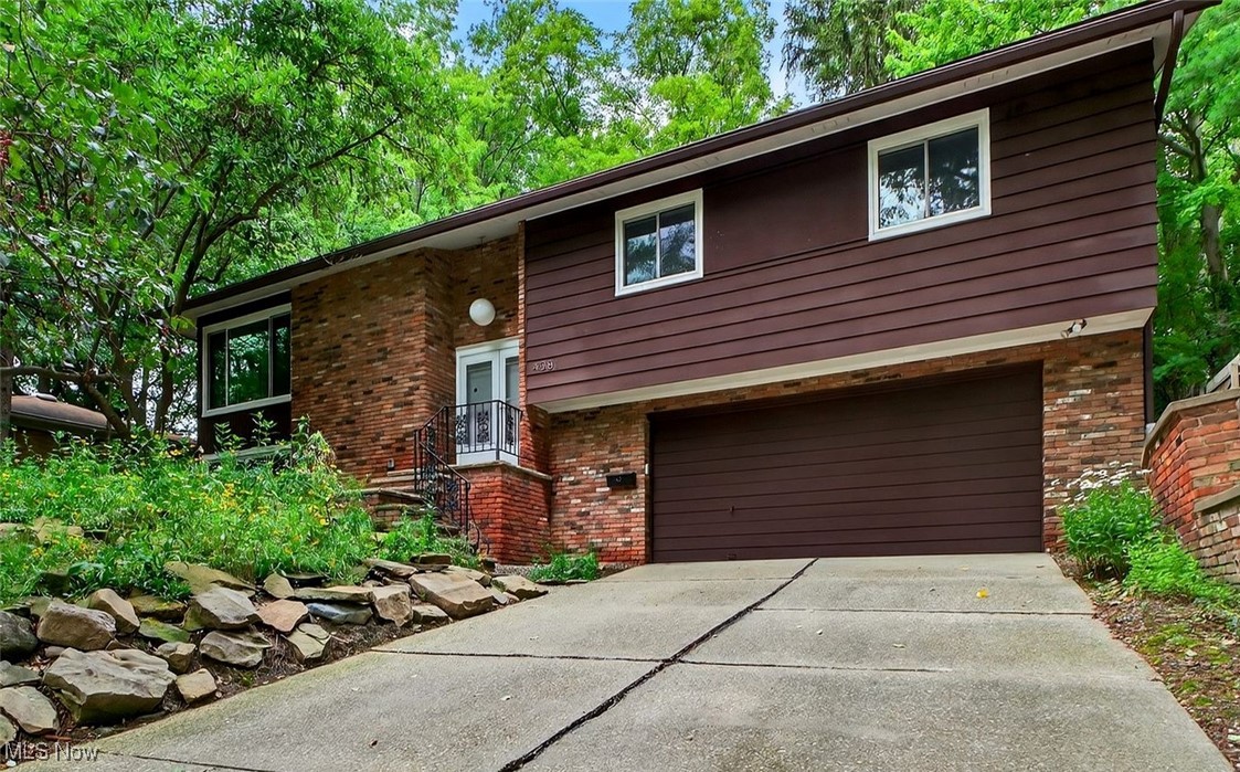 Set on a private, wooded lot in South Euclid, this thoughtfully designed mid-century modern home blends original architectural charm with minimalist, modern touches. Crisp lines, beamed ceilings, and expansive corner windows bring warmth and natural light to every room.
The main level offers an open living and dining space anchored by a stunning floor-to-ceiling brick fireplace. Newer Coretec Pro luxury flooring (2025) runs throughout the home, tying together the airy layout. Recently installed windows and a sliding glass door (2024), along with Perfect Lift window treatments (2024), add even more value. The refreshed kitchen features sleek cabinetry, updated hardware, and generous storage. Three bedrooms with ample closet space and an updated (2025) full bath complete the first floor, offering functional one-level living.
Downstairs, the finished lower level adds flexible space for a guest suite, rec room, or creative studio, along with an updated (2025) half bath and enclosed laundry area. Outside, the backyard is a hidden retreat with thoughtfully laid brick pavers, mature trees, and a winding path to a greenhouse—once home to prize-winning orchids. Set back from the street, this home offers rare privacy while remaining close to parks, shopping, and commuter routes. A unique opportunity for those who appreciate timeless design and peaceful surroundings.
