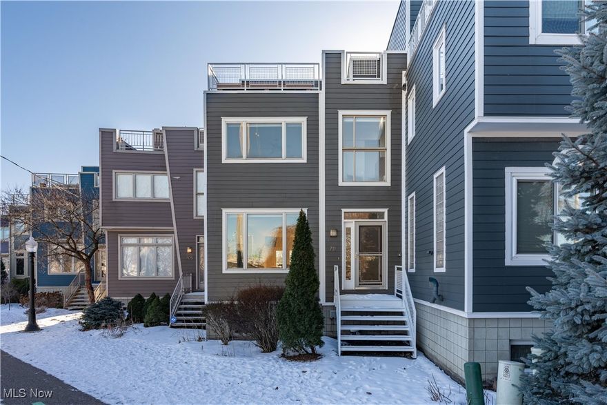 This gorgeous Townhome offers breathtaking views of the Cleveland Skyline, including the ability to watch fireworks from Progressive Field right from your private 3rd-floor walkout patio featuring a natural gas fire pit. On the first-floor, you'll find a grand entryway leading to a spacious living room with soaring ceilings and a sleek black fireplace. The open-concept design flows seamlessly into the dining area and chef's kitchen, complete with concrete countertops, a 6-burner double oven range, and a brand-new Bosch refrigerator. Enjoy another deck off the kitchen, perfect for grilling and entertaining. A half bath finishes off the first floor. The second-floor master suite boasts expansive city views through large windows. A spacious walk-in closet with built-in organizers, and a luxurious master bath featuring a glass walk-in shower, double sinks, and a brand-new bidet with a heated seat. A second bedroom, a full bathroom with stylish black tile, and a laundry room round out the second floor. The third floor is perfect for entertaining with a built-in bar complete with a dishwasher, refrigerator, and sink. Big glass sliding doors give you tons of natural light and breathtaking views. The lower level offers a flexible space for a bedroom, home gym, or additional living area, with access to a 2-car garage. Located right next to the Towpath and close to the vibrant neighborhoods of Tremont, Ohio City, and Downtown Cleveland. The entire exterior freshly painted. This home is ideal for those looking for modern amenities and the best of city living.