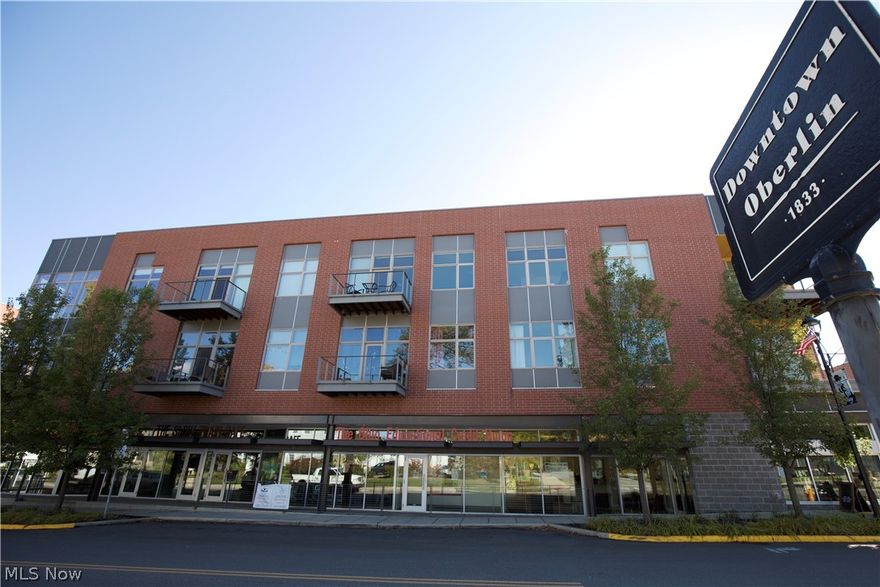This fantastic corner unit, two-story loft style, two-bedroom, two-bathroom condominium in the beloved East College Street Project features 22-foot ceilings, double height windows, southern exposure, maple hardwood floors, updated LED lights, custom window treatments, washer and dryer and an energy-efficient tankless hot water heater. This home is flooded with natural light and the great room is large enough for a grand piano. The patio overlooks the picturesque courtyard. The spacious great room flows into a modern kitchen with granite countertops and a breakfast bar/island. The second bedroom, currently used as an office/den, is on this level, as is a full bathroom. The primary bedroom is on the second floor and is lofted above the great room. The primary bathroom and laundry room are also on the second level. Outdoor parking is conveniently provided with one assigned space, and optional indoor garage parking is available for a fee. Come join this dynamic community, centrally located in downtown Oberlin. Enjoy a coffee at the Slow Train Cafe, or take in a concert at the Conservatory of Music. Visit the world-class art museum, catch a movie at the historic Apollo theater, or have a meal at one of many restaurants in this thriving and sophisticated college town.