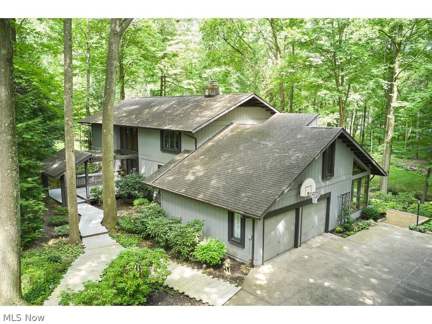 Discover the allure of mid-century modern architecture with this captivating 4 bedroom, 2.5 bath home nestled on a private 1.27-acre lot surrounded by lush mature trees in Bath Township. Built in 1973, the home boasts a distinctive architectural style incorporating cedar wood, glass, and stone throughout. The first floor features a kitchen opening into a spacious family room with soaring ceilings and expansive windows offering panoramic views of the serene surroundings. A private den, complete with a wood-burning fireplace and stone hearth, provides a cozy retreat, while formal living and dining rooms and a dramatic two-story foyer add elegance. The second floor hosts four generous bedrooms and two full baths. A partially finished walkout lower level offers an additional 800 sq ft of versatile space. With its seamless blend of indoor and outdoor living spaces, this home presents a rare opportunity to own a piece of architectural history in a highly sought-after location. Don't miss out; schedule your private appointment today!