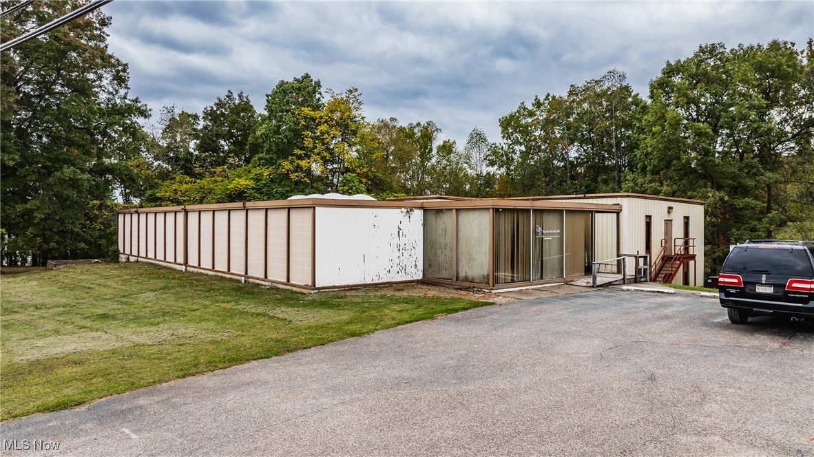 The top floor spanning over 7,500 square feet +/- for a total of 18,360 square feet for this Commerical building. This versatile multilevel office complex is located just outside the city limits, offering both privacy and convenience. Formerly the site of Borg Warner’s drafting and print space, it’s currently used as an oil and gas office but could be easily transformed into multiple business offices or a rehab facility. The top floor features a reception area with restrooms and a kitchenette, nine office spaces, a server room, and two spacious conference rooms. A connector leads to the west wing, which includes an oversized conference room and seven more office spaces.
The open-air atrium provides access to the lower level, complete with an updated kitchen, bathrooms, three large office spaces, and ample file/storage rooms. Conveniently located near the I-77 interchange, the Wood County Airport, and the Route 31 interchange, this property is wired with CAT5 for high-demand computer and multi-phone services. Additionally, the Mid Ohio Valley Transit Authority is planning to extend bus services to Route 31, enhancing accessibility.