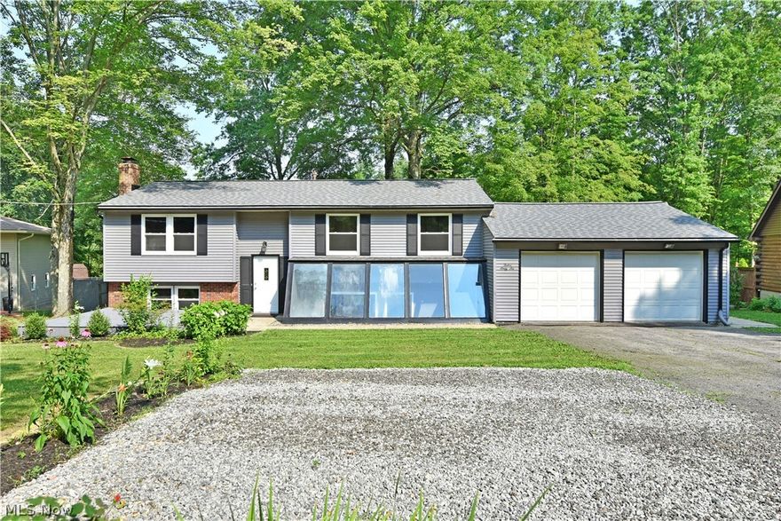 A truly hidden gem, this masterfully remodeled split level offers up move-in-ready living space with a big, sun-filled surprise below! Taking a quick glance at the handsome exterior of this tree lined property, you’ll quickly notice its unique, glass lower atrium. The design allows for all weather entry from the garage to the lower floor of the home, where the natural light pours into a stunning rec space, complete with bar area and fireplace. For more scenic views, take advantage of the finished sunroom that overlooks the grassy backyard, or spend time on the substantial rear patio. Through the front door, and up the stairs of the tiled foyer to the main floor, the residence continues to delight with an open floor plan that showcases its natural-colored hardwood styled flooring and soothing gray and white color scheme. The sizeable kitchen awaits with stainless touches amongst the bright white cabinetry as dining can be found around the corner. Three inviting bedrooms enjoy carpeted f