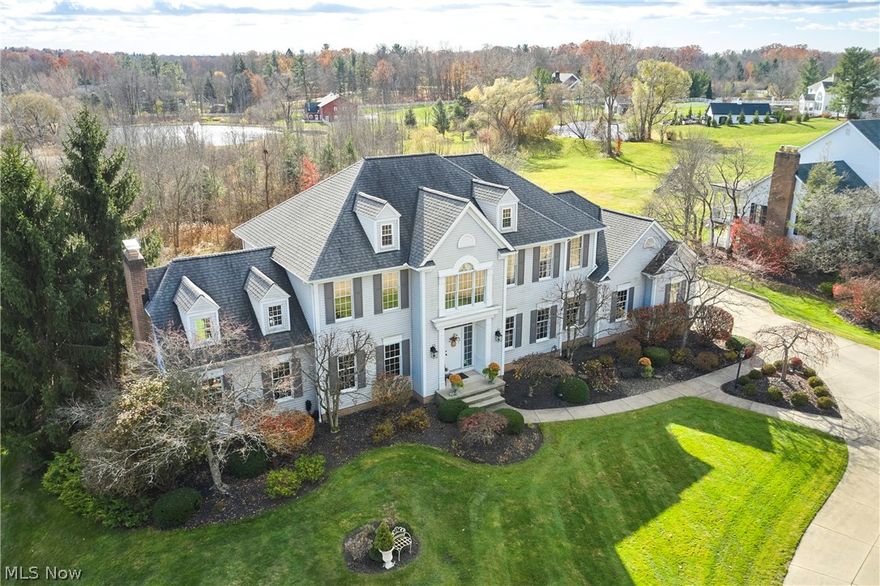 A private sanctuary with engaging entertainment spaces is what you will find as you pass through the white rail fencing to experience this glorious Custom Prestige Colonial. Enchanting, lush gardens and professional landscaping offer a warm welcome. Enter through the stately front door into a beautiful foyer revealing glimpses of elegance within. The formal living and dining
rooms feature 9-foot ceilings, crown molding, and large windows that bathe the space in light. The expansive eat-in kitchen truly feels like home, boasting a breakfast bar, granite countertops, a center island, abundant cabinetry and expansive windows. Step down into the vaulted family room, highlighted by windowed dormers and a floor-to-ceiling brick wood burning fireplace. The two-level garden room addition with terracotta floors, surrounds you with sunlight and panoramic views, offering seamless access to the deck overlooking your two-acre estate. The main floor also hosts an office, a large half bath, laundry room, and three-car garage access.
Upstairs, the primary suite features a private sitting room, large bathroom with travertine shower, floor and soaking tub, and walk-in closet. Two additional bedrooms each include bathrooms and generous walk-in closet spaces. The lower level is a versatile retreat with a media room, gym or playroom, additional bedroom, and full bathroom, plus a recreation room and solarium with terracotta floors and easy access to the outdoors. The focal point of the outdoor patio is a stunning stone waterfall, with a firepit and ample room for dining and socializing.  Enjoy sidewalks to Downtown Hudson’s premier shopping, dining, and a 5-star Library!