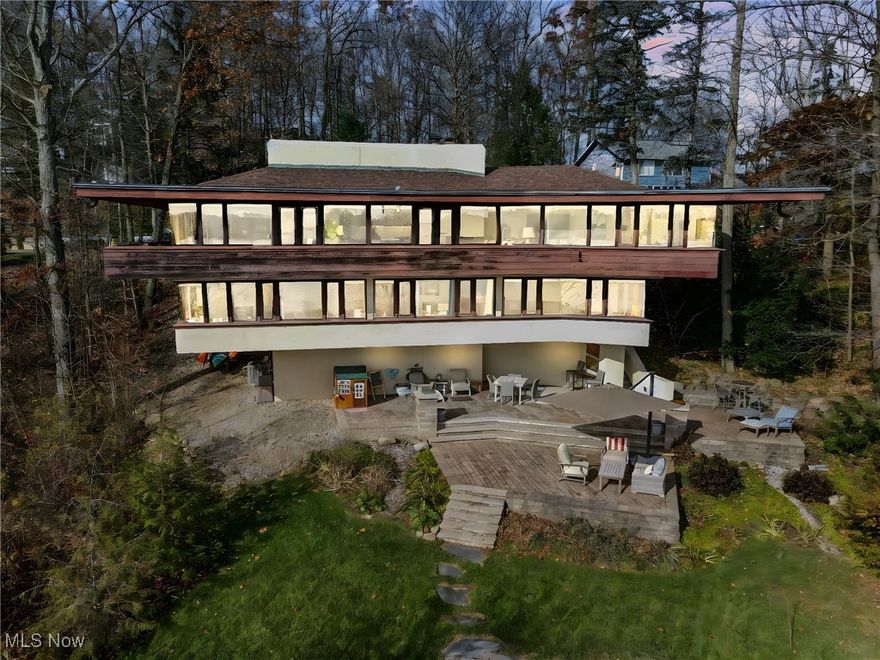 Inspired by Frank Lloyd Wright, this stunning lakefront home is a Mid-Century Modern masterpiece in desirable Twin Lakes. Perched on a hillside overlooking West Twin Lake, it offers dramatic rooflines, wrap-around balconies, and floor-to-ceiling windows that bring the outdoors in. The redesigned chef’s kitchen features rich redwood cabinetry, updated backsplash, Thermador top-of-the line appliances, custom floating shelves, and custom built island with pop-out cabinets and bar seating. The open layout flows into the dining and living areas, where walls of windows capture breathtaking sunrises. Cozy, newly upholstered built-in seating and a gas fireplace create the perfect setting for winter evenings.  Thoughtfully curated details include warm redwood accents, built-in cabinetry, integrated lighting, refinished concrete and luxury vinyl tile flooring. This 4–5 bedroom, 2.5-bath home provides flexible spaces for modern living and work. The primary suite wing offers that magnificent view, deck access, walk-in closet and updated bath with walk-in shower & there's a sitting/office area. A lower-level family room adds another comfortable gathering space.  The walkout lower level leads to a spectacular three-tier Unilock patio system that cascades down the hillside, offering multiple areas for dining, entertaining, and enjoying panoramic lake views. Launch your kayak from your backyard and enjoy the seamless indoor-outdoor lifestyle this home was designed to deliver.  With its overhanging eaves, horizontal lines, and strong connection to nature, this home is a true work of art. Updates include: built-in sofa cushions (2024); updated bathrooms (2023); redesigned kitchen, gas fireplace conversion, refinished concrete floors (2022); custom trim (2021); LVT flooring and hot water tank (2020); new furnace, AC, and front stucco (2018); three-tier Unilock patio and replaced skylights (2016).  This property is a rare, one of a kind, iconic property—and not to be missed.