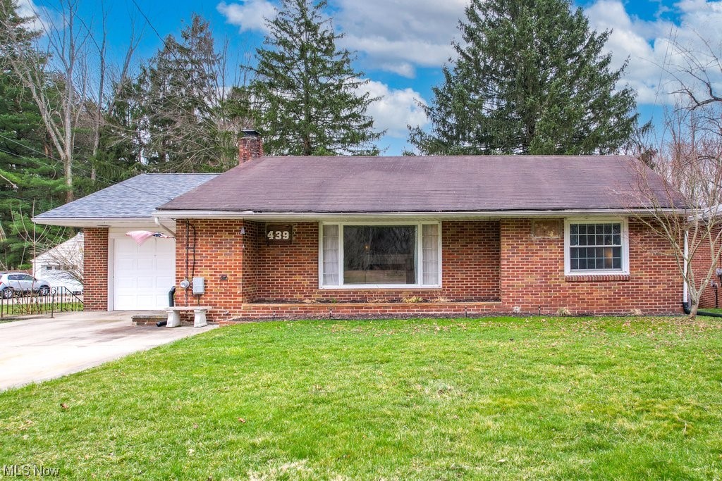 Adorable and updated mid-Century brick Ranch home in the heart of Ravenna features 3 Bed / 2 Bath, nearly 1200 sq. ft of living space, gleaming hardwood floors, and neutral paint throughout. On the main level resides a spacious and inviting Living Room with a large picture window and a decorative brick fireplace and mantel. A bright eat-in kitchen is sure to please with its plentiful natural wood cabinets, Corian countertops, and newer appliances and low maintenance luxury vinyl plank flooring. The versatile third bedroom which can be accessed through both the kitchen and hallway could also be used as an office or a formal dining room - your choice! The clean and dry partially finished walkout basement includes a laundry area (washer and dryer included), a 2nd Full bathroom with walk-in shower, and a recreation room that has potential to be used as a 4th bedroom that also features an illuminated wet bar that is perfect for entertaining. The tree-filled .78 acre lot includes a concrete