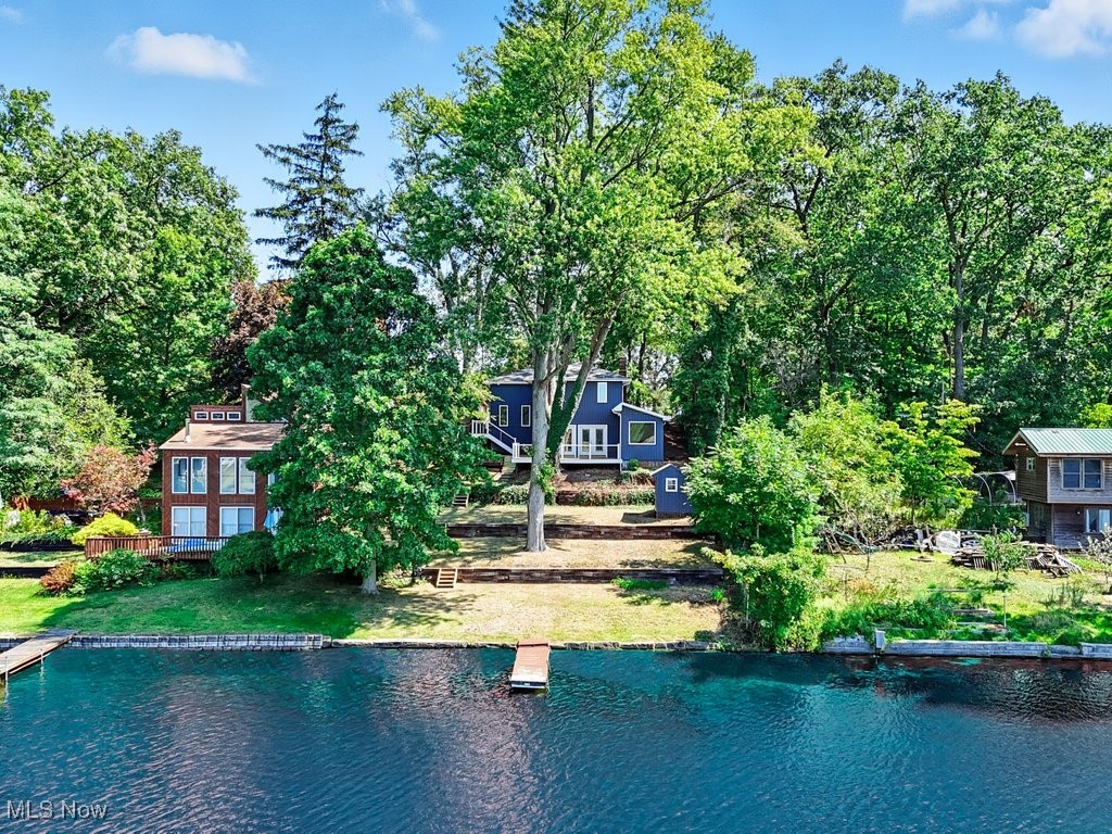 Peaceful living awaits at this stunning lakefront home - your personal sanctuary tucked away on beautiful Hower Lake, adjacent to the North Reservoir. No stone was left unturned with its recent renovation - so grab your kayak, then move right in and begin your new chapter on PLX. The stone facade and striking blue vertical siding give it instant curb appeal, but - nothing beats the view from the lake! From your private dock, you look up at the large multi-tiered yard, adorned with mature trees and stairs leading to the new deck & brick patio - offering a tranquil setting for watching the sun rise & set over the water. Double French doors lead you into the open concept main living area and modern kitchen with SS appliances, granite counters, a subway tile backsplash, durable LVP flooring, recessed lighting, and ample cabinet space. A cozy side office features built-ins w/granite, a vaulted ceiling, and a large picture window - providing serene views and evoking a sense of calm. Head upstairs via the side-entry foyer to explore the spacious Primary Suite w/its own wood burning fireplace, and the ensuite bath - a spa-like retreat w/a large soaking tub, walk-in shower, double-vanity w/granite, a skylight, and its own lake view. Two additional bedrooms, a second updated full bath, and access to the attached garage complete the upper level. In addition to storage and utility closets on the lower level, the shed allows for additional space to store your equipment & fishing gear. A new roof, windows, doors, water heater/softener, updated HVAC, and several other recent improvements complete this rare find in Portage Lakes. Opportunities abound - whether it becomes your primary residence, summer home, or another revenue stream as a short-term rental. The choice is yours - schedule your showing today!