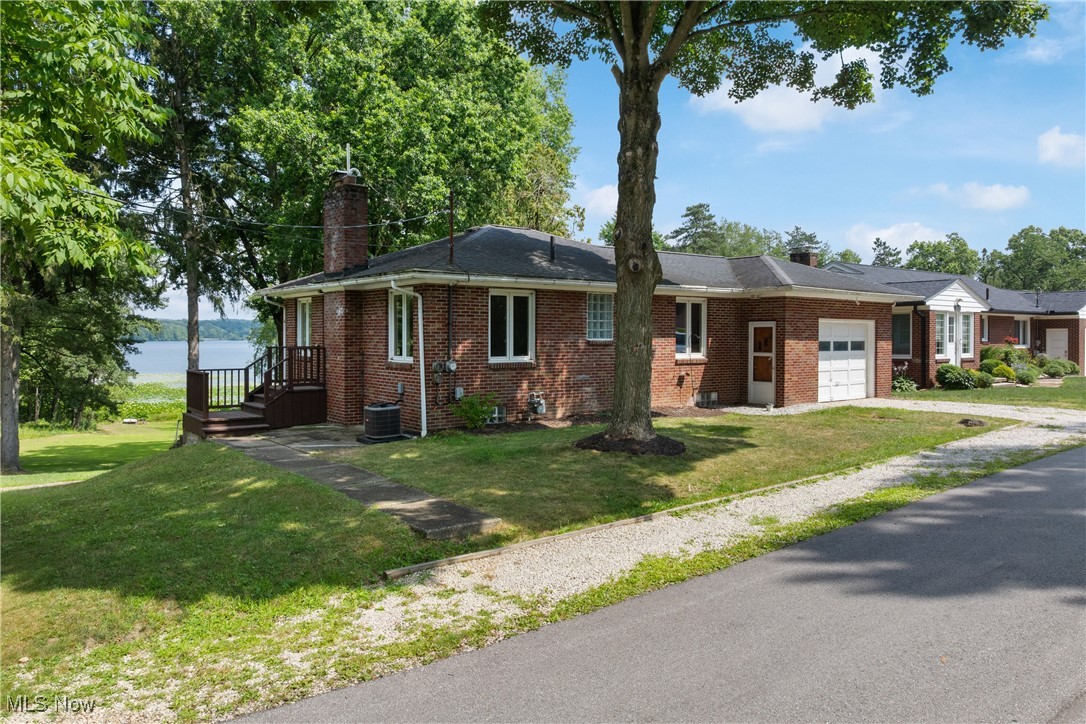 Why say you'd rather be lost at the lake than found at home, when you can make your home AT the lake? This is a rare opportunity to own a property on the shores of 753 acre Nimisila Reservoir, part of the beloved Portage Lakes and managed by Summit Metro Parks. With peaceful waters and spectacular sunrises to greet you each morning, this home offers a lifestyle that’s truly one-of-a-kind. Nestled in the Green Local School District, this solid brick ranch offers a walk-out lower level and a one-car attached garage. Inside, you'll find three bedrooms—including one in the lower level—two full bathrooms, and a finished rec room. Hardwood floors run throughout the main floor, and the kitchen features newer stainless steel appliances. The peaceful, remodeled sunroom with newer windows offers a front-row seat to nature, while the lower covered patio invites you to relax and take in the view of the water just steps away. Set on the edge of parkland, this property offers effortless access to kayaking, paddling, world class fishing including bass, pike, walleye, bluegill, crappie and yellow perch, and some of Ohio’s best birdwatching. Nimisila Reservoir is a 742-acre lake and a sanctuary for wildlife, with only electric motors permitted to preserve its quiet, natural setting. You’ll spot bald eagles, osprey, and enjoy front-row seats to the globally renowned Purple Martin migration. Important updates include a new air conditioning system and garage opener with keypad, both installed in 2022. Major tree removal to open up lake views 2024. The county well and septic point-of-sale inspection has been completed and passed, offering added peace of mind. Swingset, paddleboat and washer and dryer convey. There are very few homes that border this nature-lover’s paradise and even fewer that combine lake views with easy access to the water. This is your chance to turn the lake life from a "getaway" into your "everyday". Come see it—and make it yours.