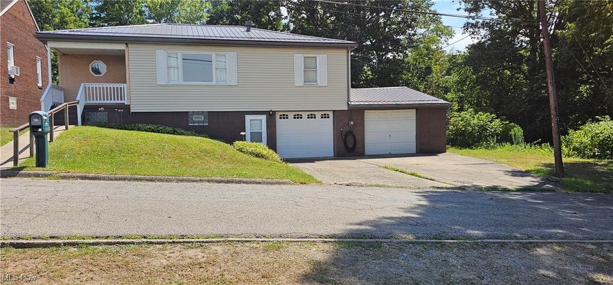 WELCOME to 136 Mahan Rd, Weirton, WV - and yes, this home will come with a HOME WARRANTY! This raised ranch style home offers 3 bedrooms, 1 and a half bathrooms, and DRY, partially finished basement where you will find a recreation room featuring a bar with a refrigerator, sink and bar stools, a 50" TV, couch, and electric fireplace.  
On the main floor you will observe a bright and spacious living room, an eat in kitchen equipped with all appliances, 3 roomy bedrooms, and a full bath.  Enjoy having your morning coffee, relaxing in the evening, or hosting a BBQ on the large, covered back patio leading out to the generously sized and fully fenced backyard.   As you walk down the stairs to the basement, you will be welcomed into the finished recreation room that is perfect for entertaining or just relaxing.  You will also find the laundry room, ample storage spaces, a half bath and access to 2 attached garages.  Did I mention that the basement is completely DRY?!  Don't miss your chance to tour this well-maintained, move-in ready home.  Contact me or your agent today to schedule a showing!